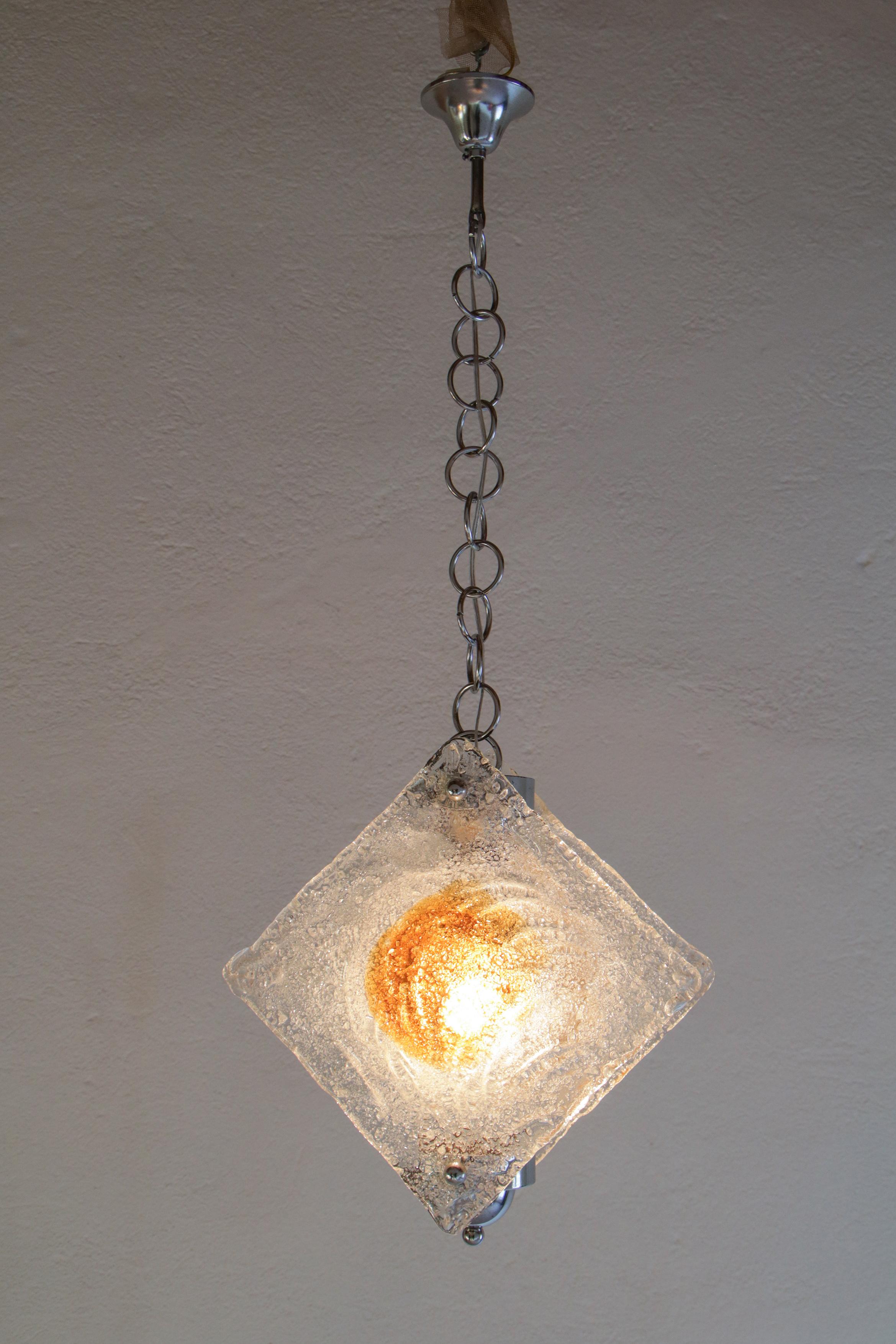Charming Italian mid-century Murano glass pendant or hanging lamp per Mazzega fashion house, from the 1970s. Blown Murano glass in amber clear color with chromium steel structure. The restoration of this mid-century pendant lamp was made with great