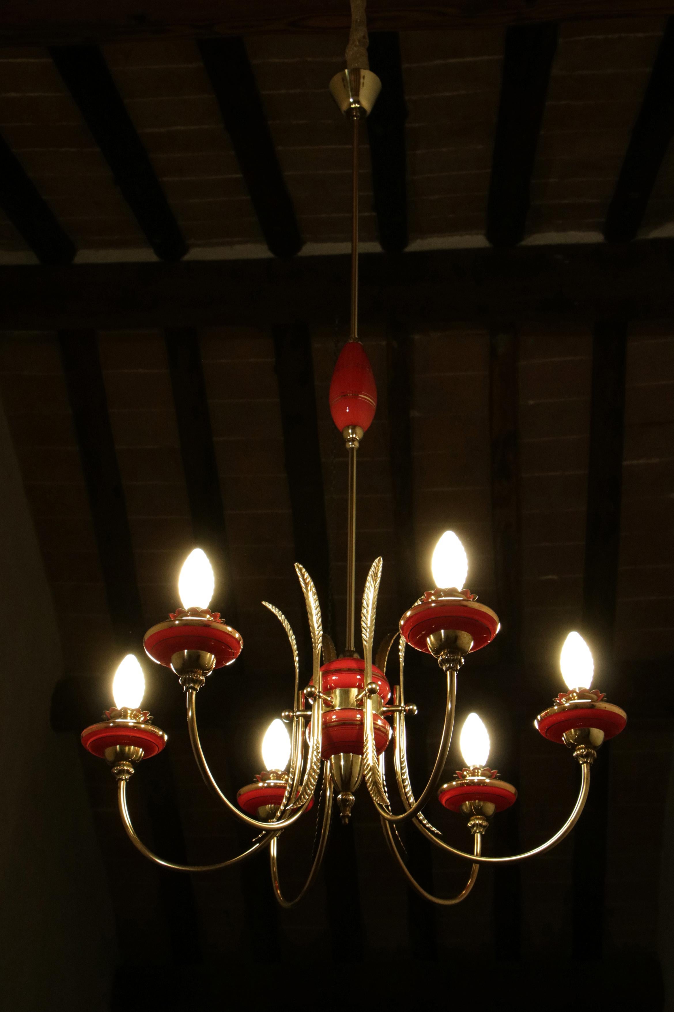 Beautiful Italian Mid-Century Modern chandelier with six lights from the 50'. The structure is made of high-quality antique brass and red Murano glass with gold color details. Gio Ponti's models inspired this chandelier, and it is a splendid example