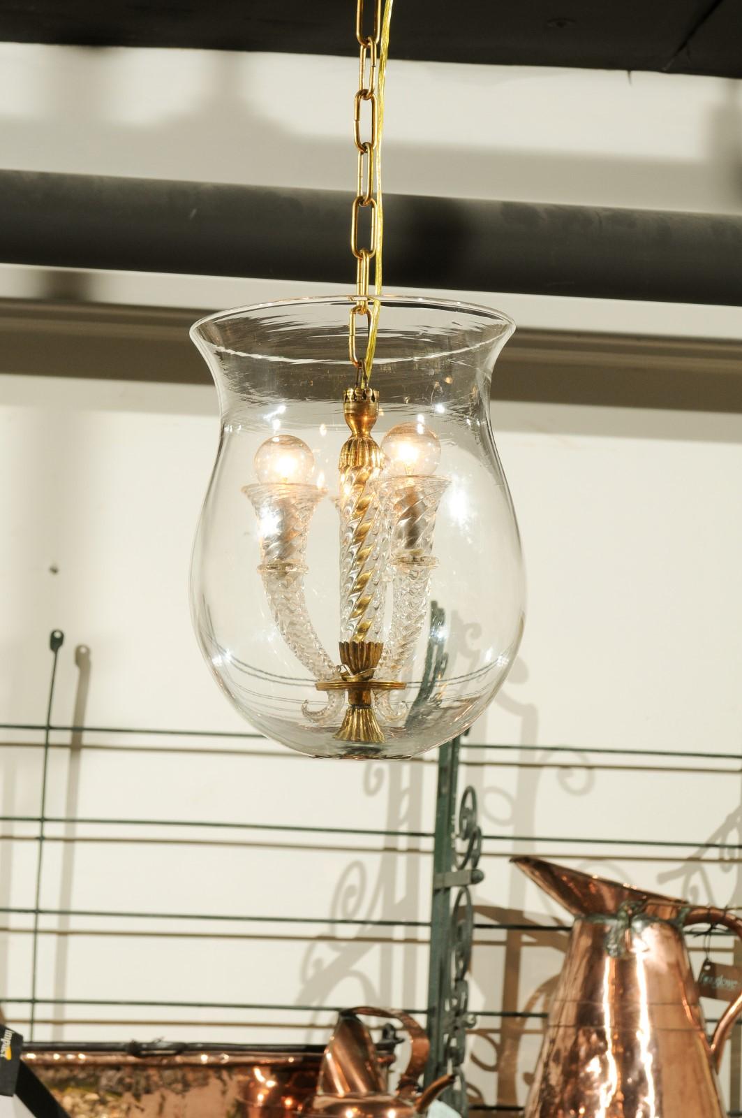 An Italian vintage Murano cloche pendant from the mid-20th century with three-light and twisted volutes. Born on the island of Murano during the mid-century period, this exquisite pendant features three voluted arms with twisted accents safely