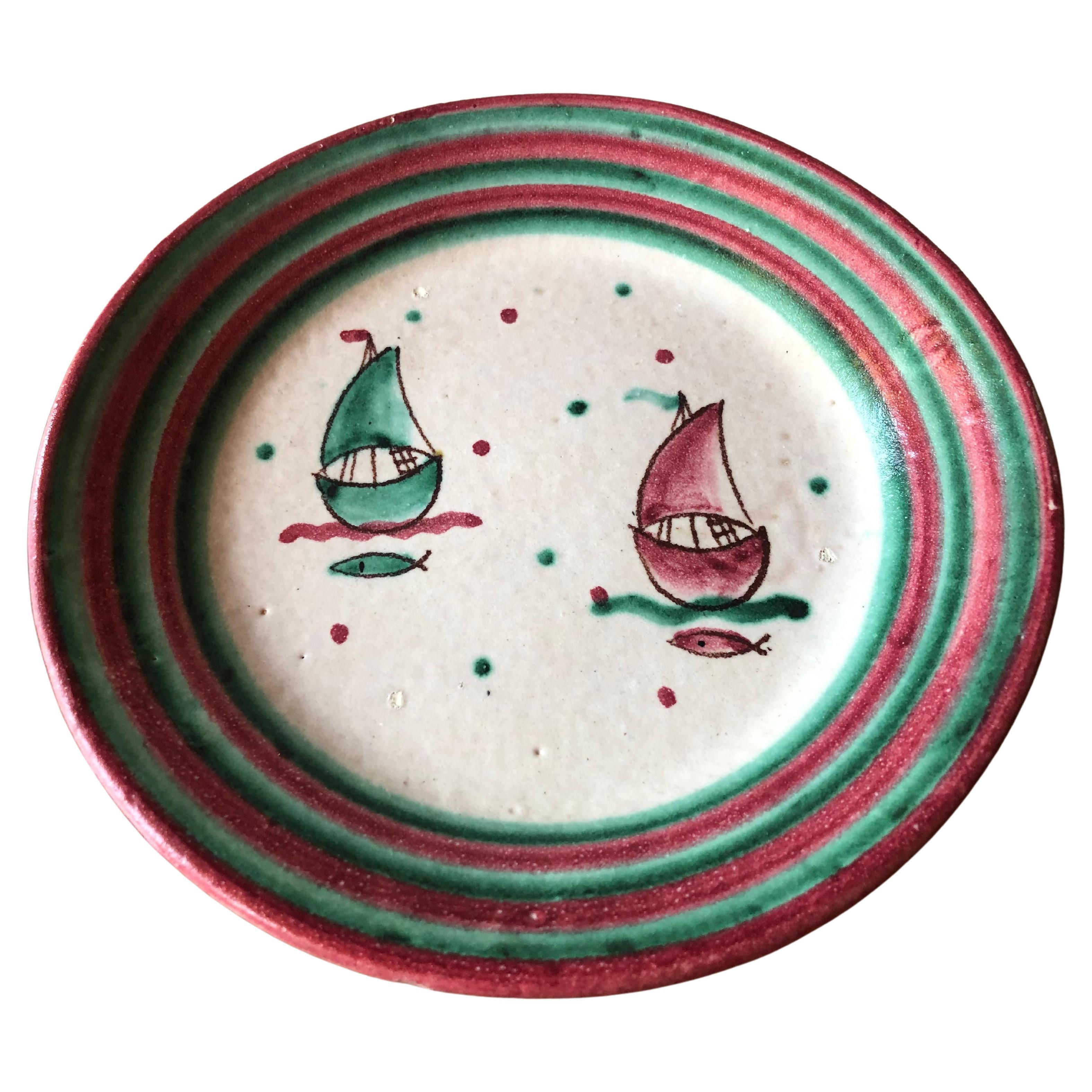 Mid century Italian stoneware centrepiece plate hand painted in shades of green and pink, with sailboats and fish swimming in the sea. 

