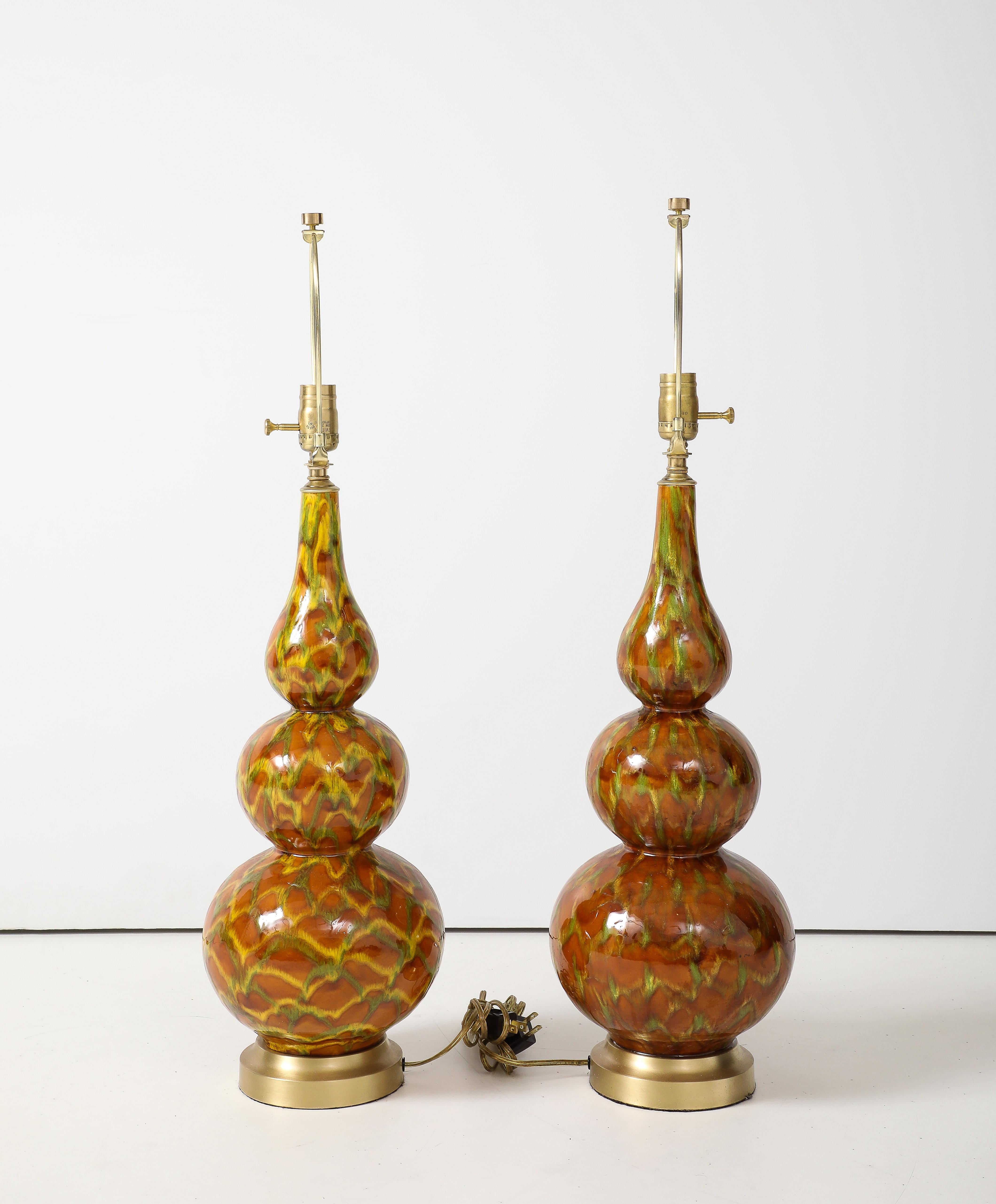 Modernist pair of hand decorated ochre glazed ceramic lamps with a gourd/sinuous shape mounted on satin brass bases. Rewired by a professional electrician for use in USA. 100W max