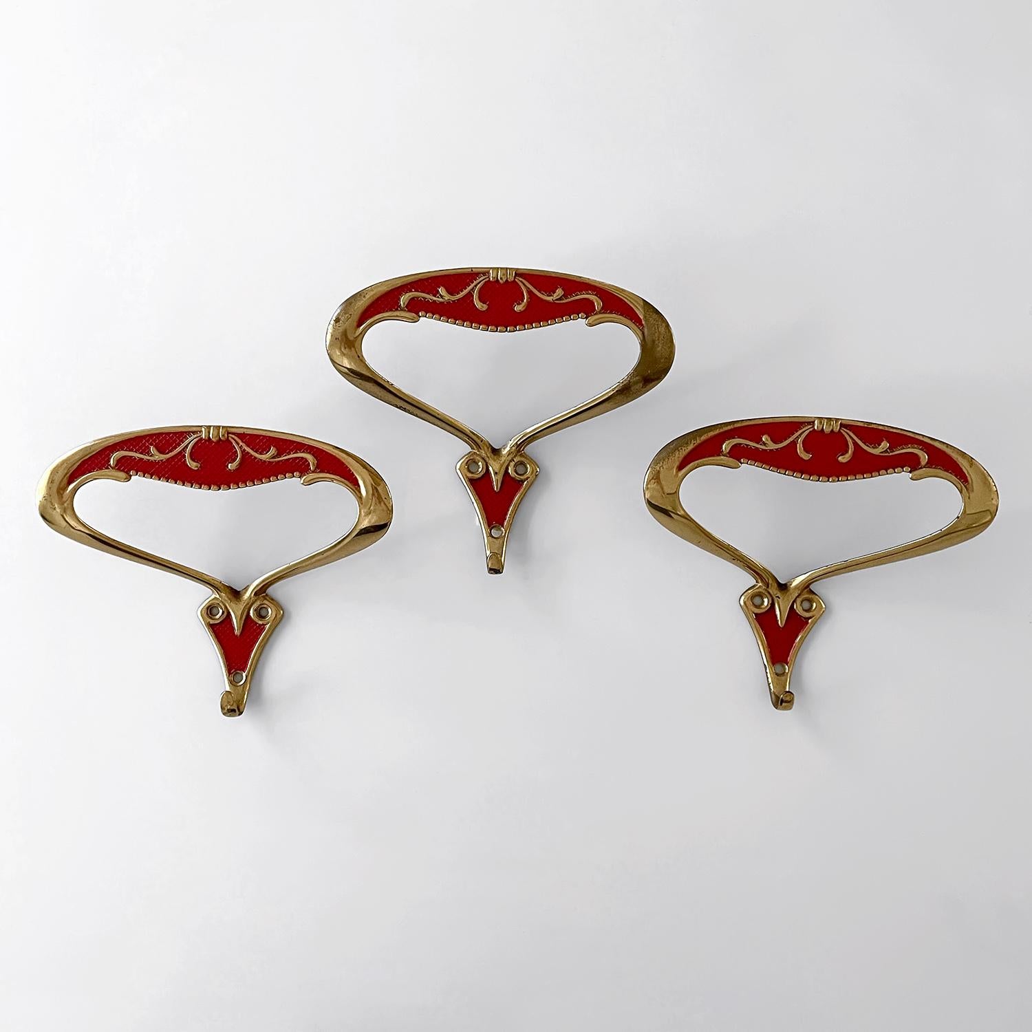 Ganci da parete in oro rosso italiano  
Italia, circa anni '50
Ogni gancio offre un ampio spazio di archiviazione con un gancio superiore ad arco per pannelli larghi e un gancio singolo inferiore.
I dettagli in rilievo sono splendidamente