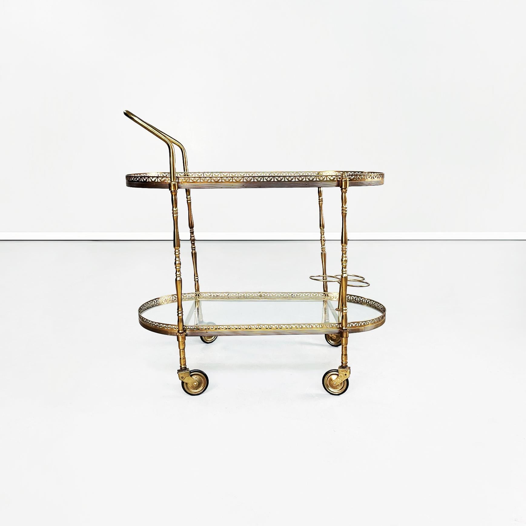 Italian mid-century oval bar cart in brass and glass, 1950s
Brass oval food trolley. The two tops are made up of two sheets of transparent glass resting on a finely worked brass structure, on the lower one there are three bottle holders. The bar
