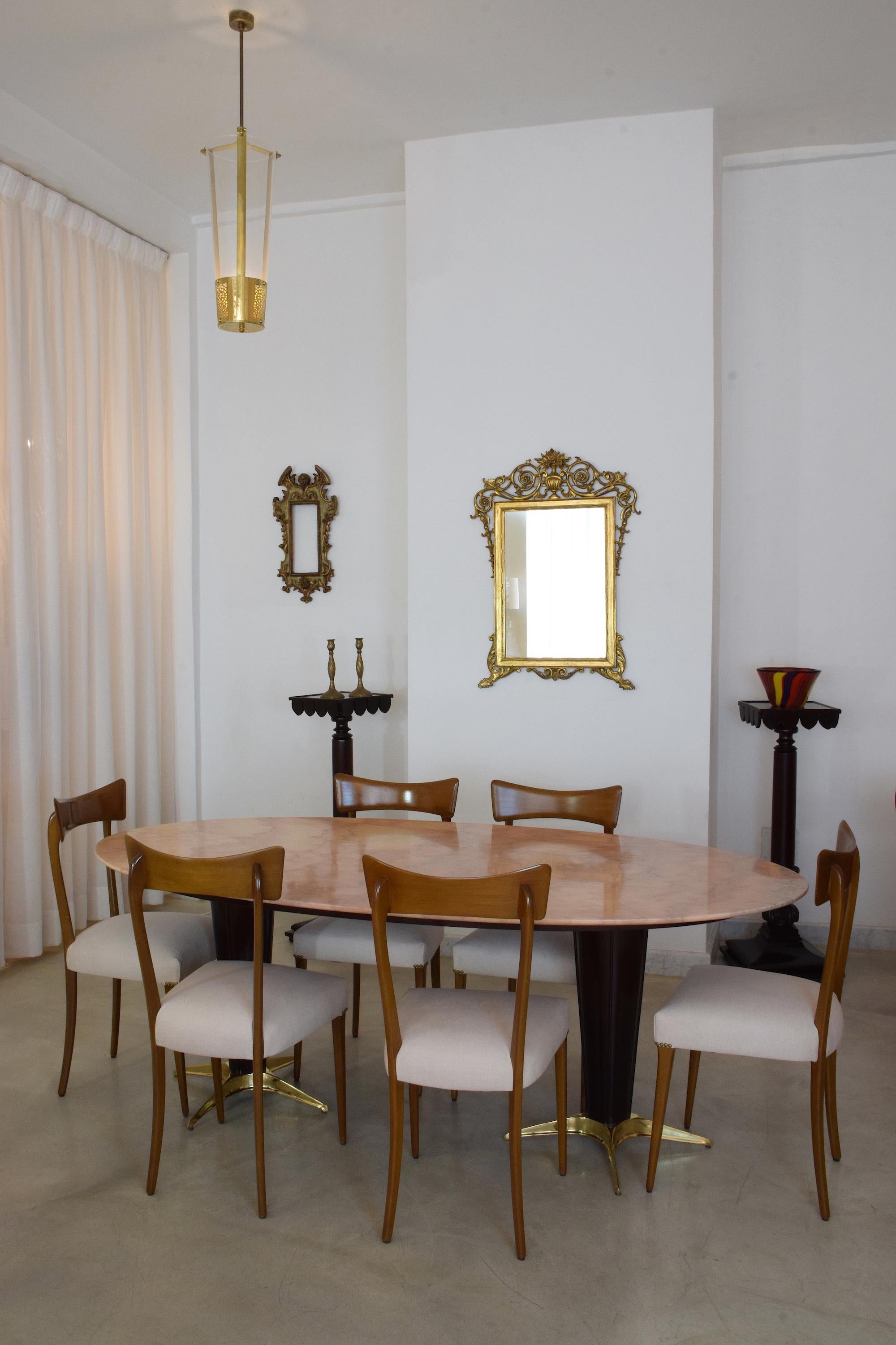A 20th century vintage big 8 seater vintage oval dining table composed of a Rosa Portuges pink marble tabletop and a mahogany veneer structure with sculptural star-shaped solid brass endings.
In restored condition with new finishing, polishing, and