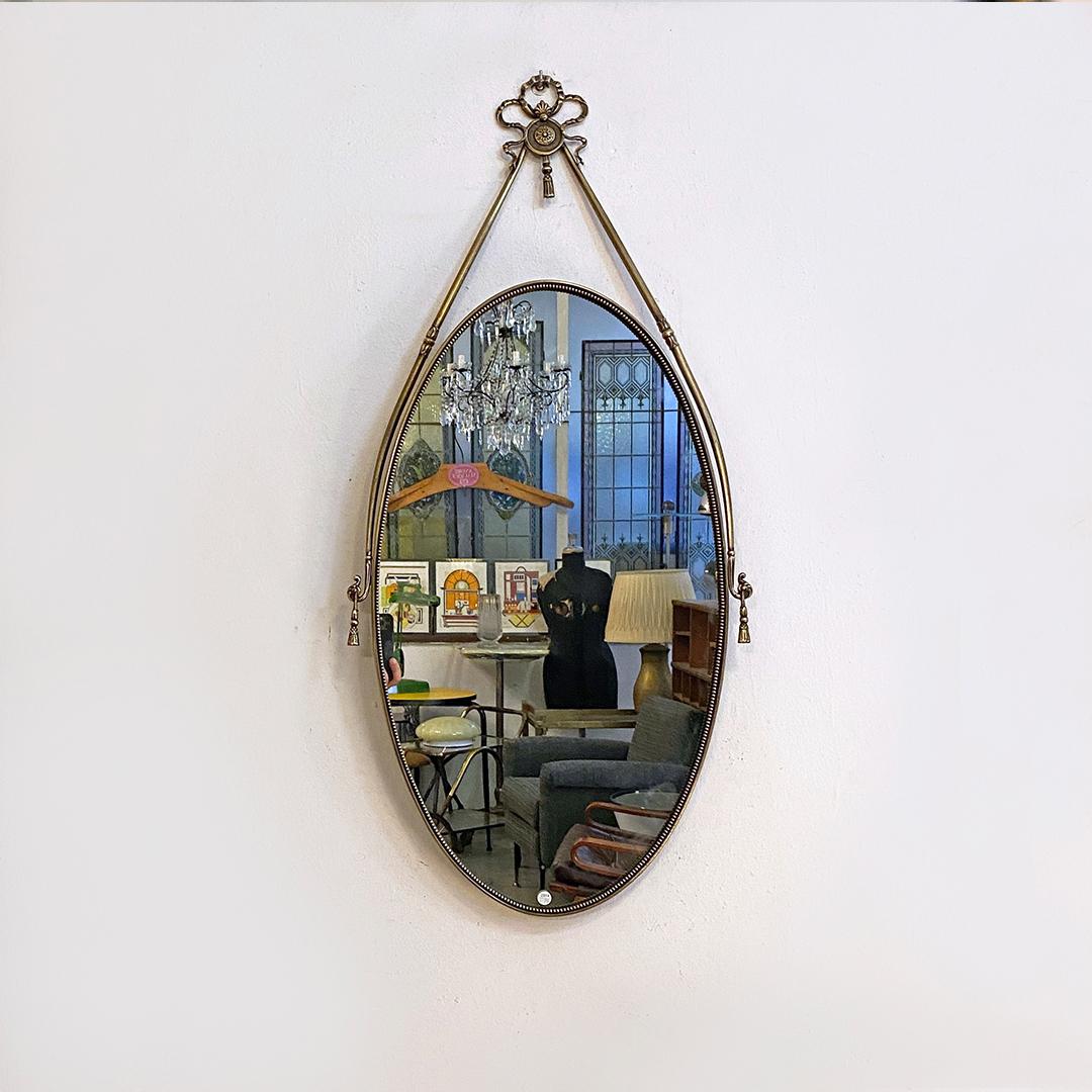 Italian mid-century oval shaped brass mirror with decorative structure, 1950s 
Oval-shaped mirror with brass edge, frieze in the upper part and external decorative structure that also makes it tilting according to the location.

Good general