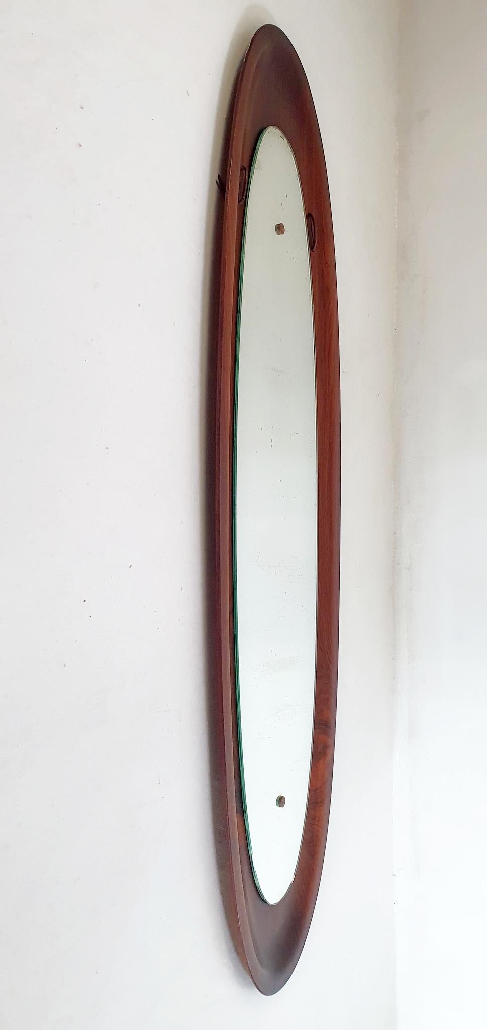 An oval wall mirror in pressed teak wood reminiscent of a surfboard. The glass has beauty spots but can be replaced upon purchase for an additional cost. Besides the glass the wood frame is in very nice condition without breakage or blemishes.