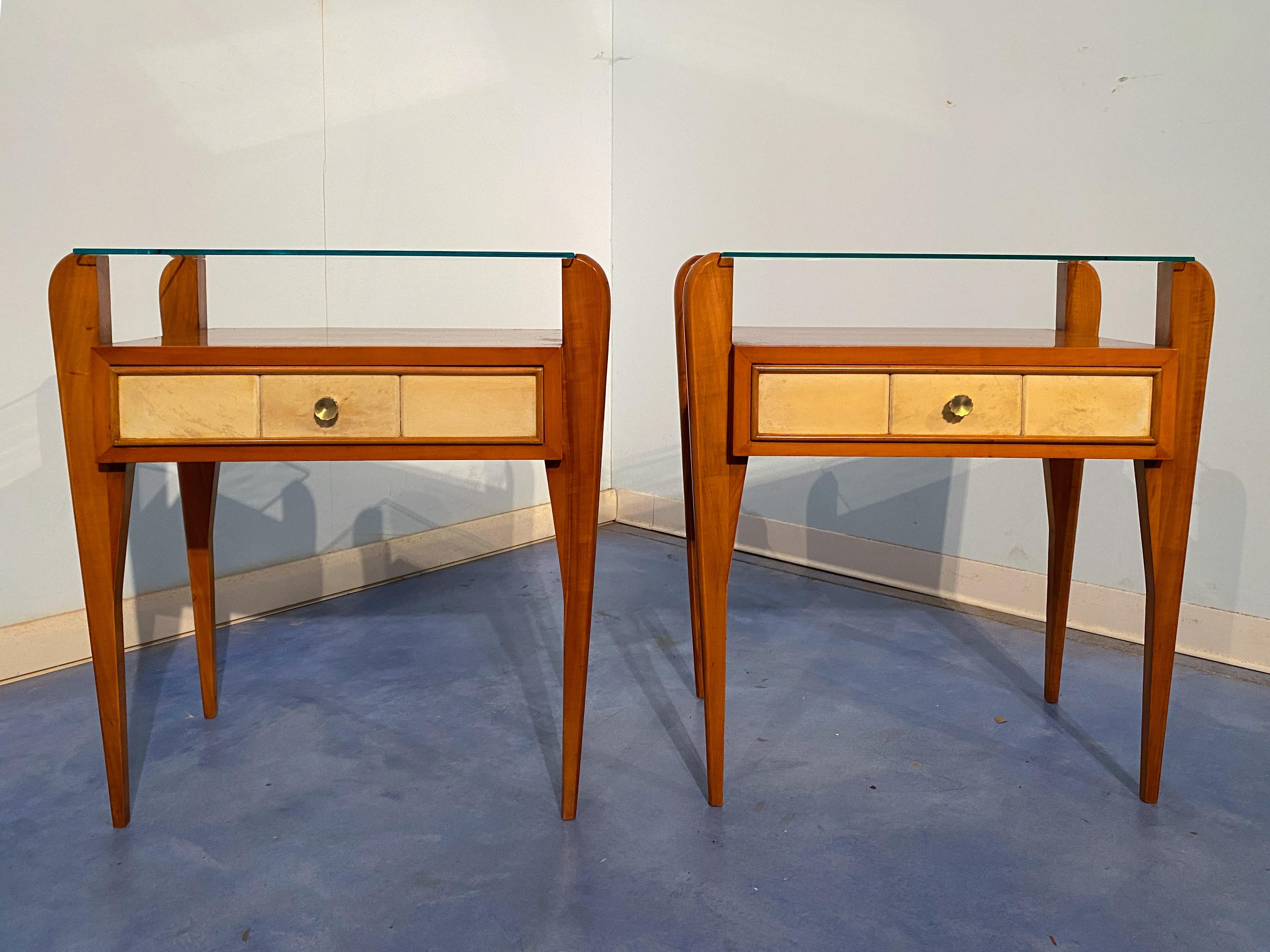 Osvaldo Borsani designed these splendid parchment and cherry bedside tables in the 1950s. The upper shelf is glass, with an elegant and slender design. Drawers are covered in parchment. Original of the period, divided into three sections on the