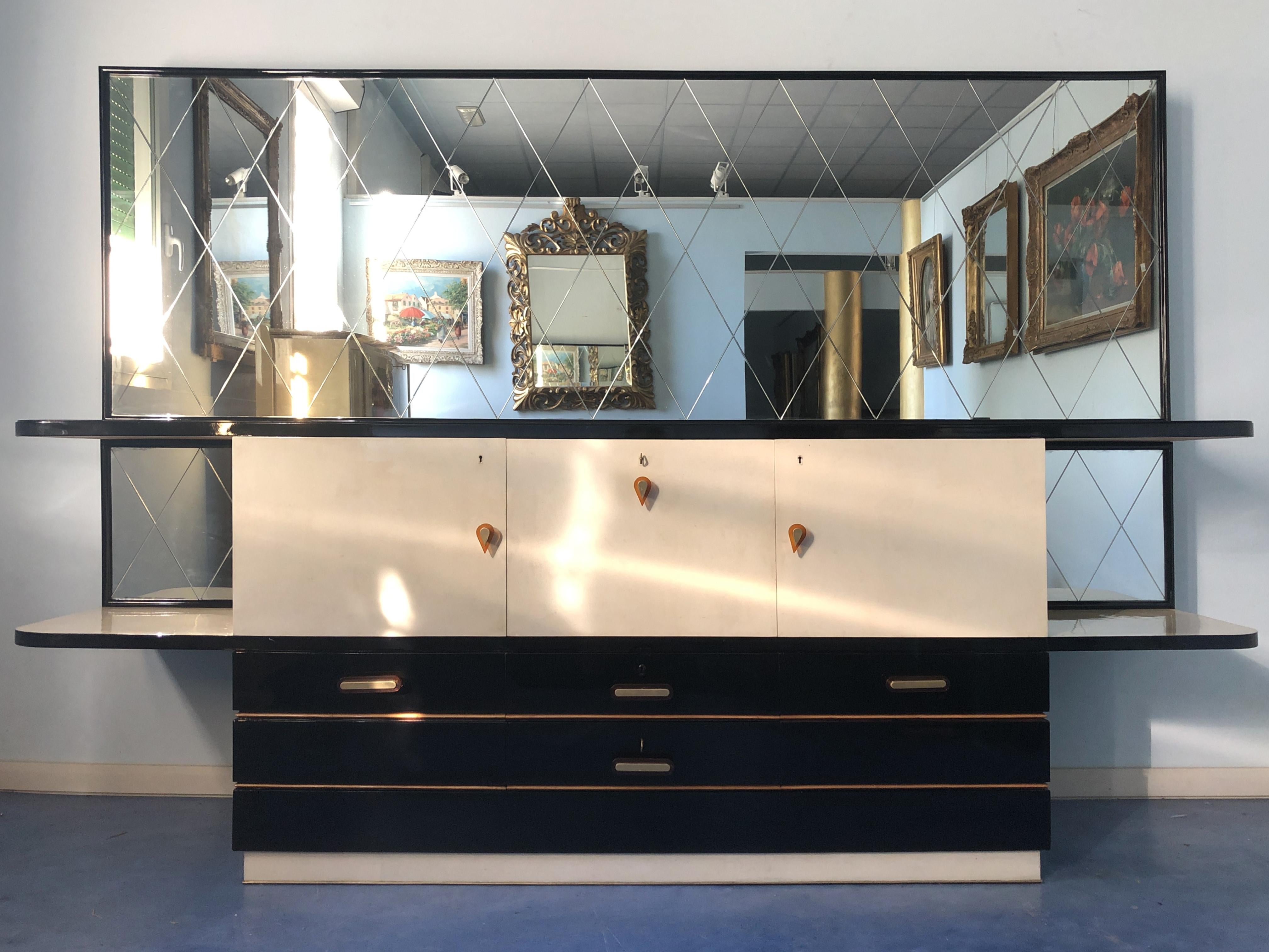 This Italian midcentury sideboard has splendid contrast movement of the lines, the lower part is lacquered in black, the design takes influence from the geometric rationalism form, the higher part has interesting demilune shape.
The interior is