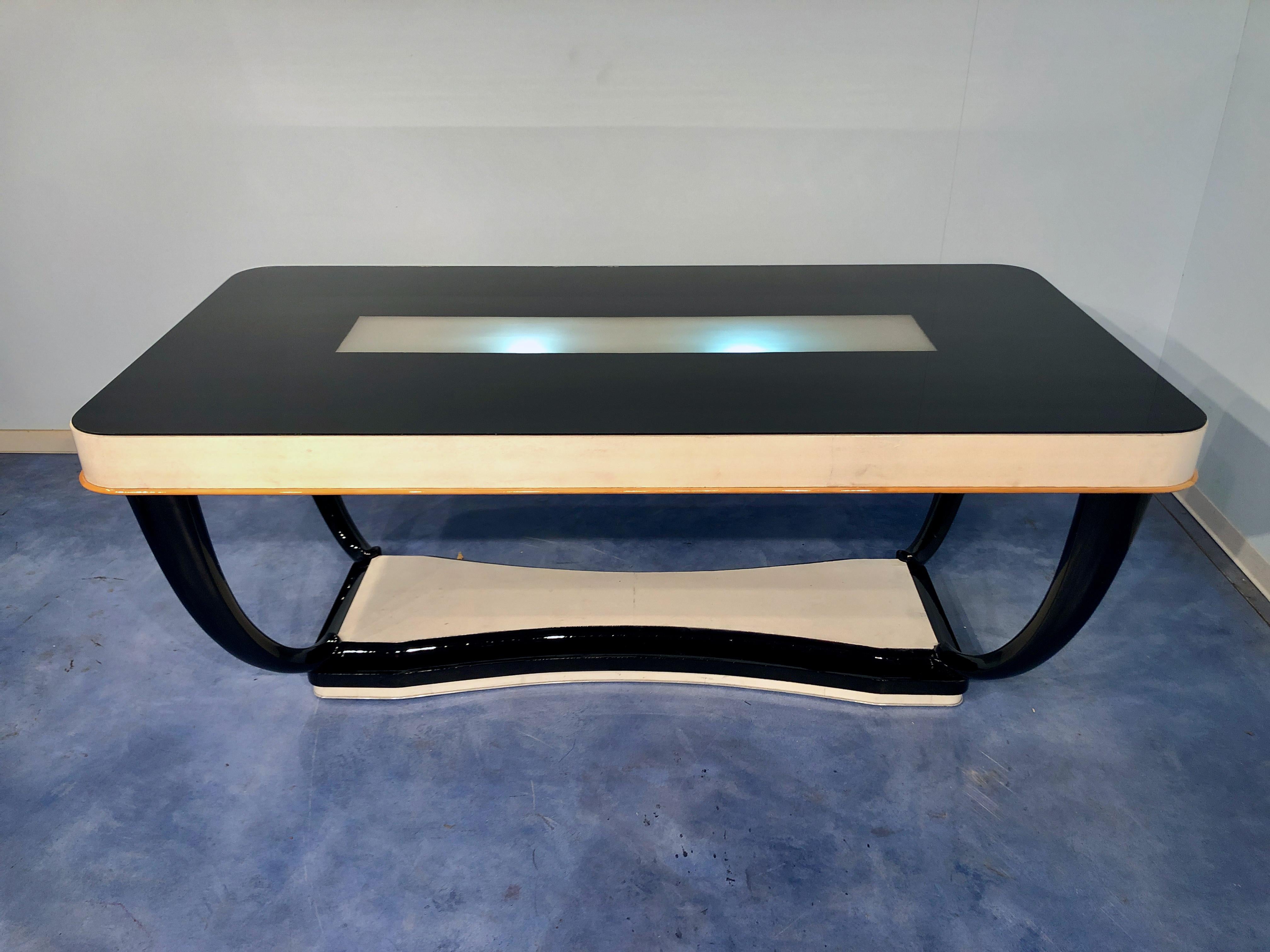 Luxurious and stylish Italian midcentury parchment dining table with an illuminated black glass top. The table legs are really elegant in black lacquered mahogany wood. The tableside is in parchment, you can notice a maple line on the final part.