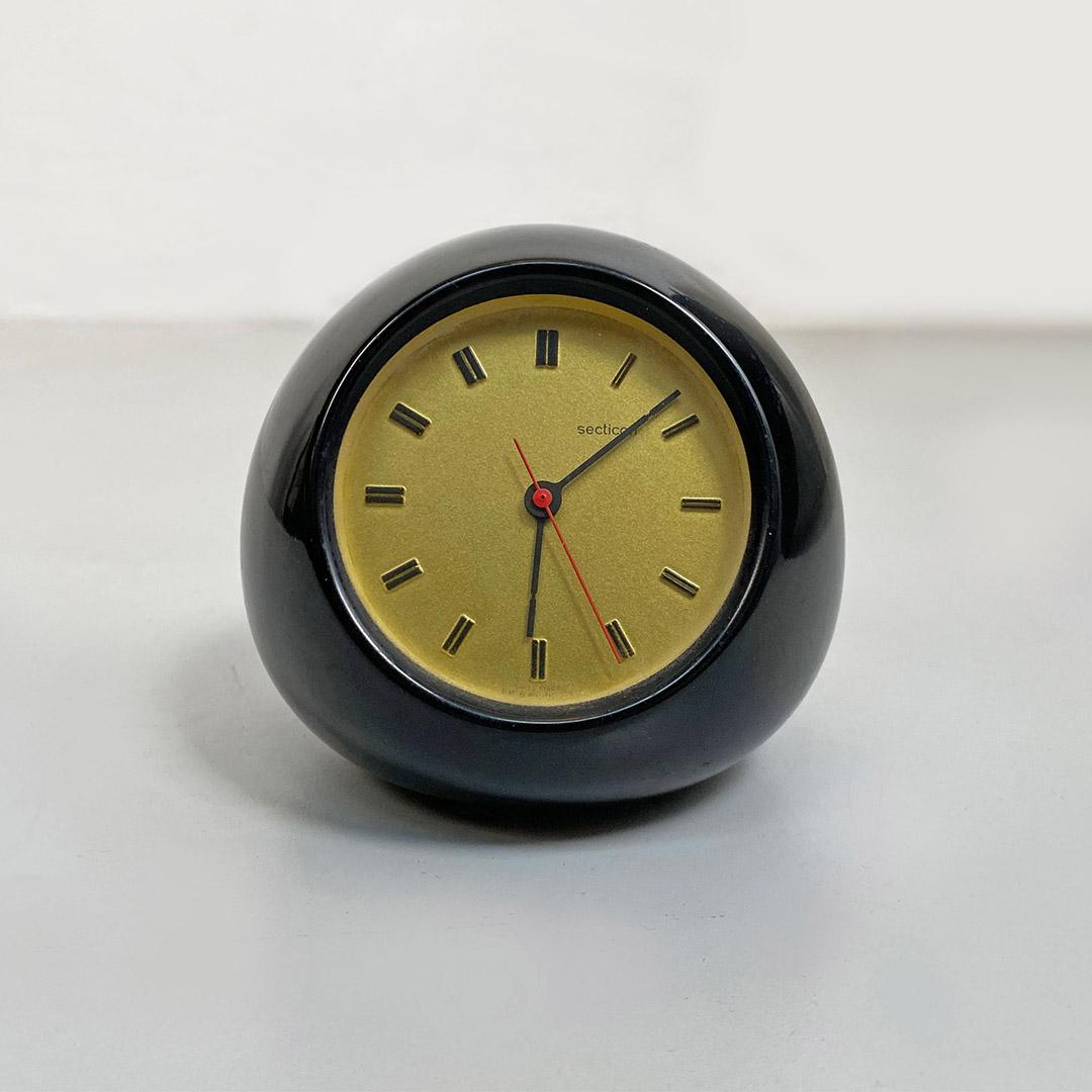 Italian Mid-Century Modern gold and black plastic Section T2 table clock by Angelo Mangiarotti for Portescap, 1956.
Table clock Secticon T2 model, with a rounded shape, in black plastic with a round gold-colored dial.
Project by Angelo Mangiarotti