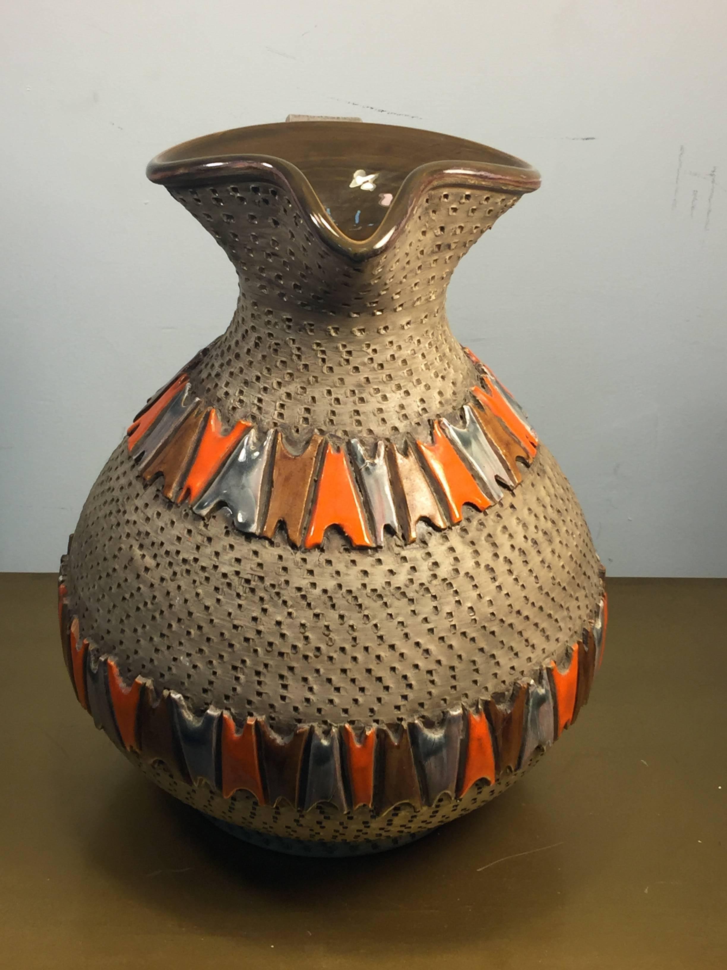 Italian pottery pitcher formed in the Brutalist manner with brown rough textured background and geometric glazed designs in deep brown, orange and gray. Created in Italy, circa 1950s-1960s, the base measures at 6 1/2
