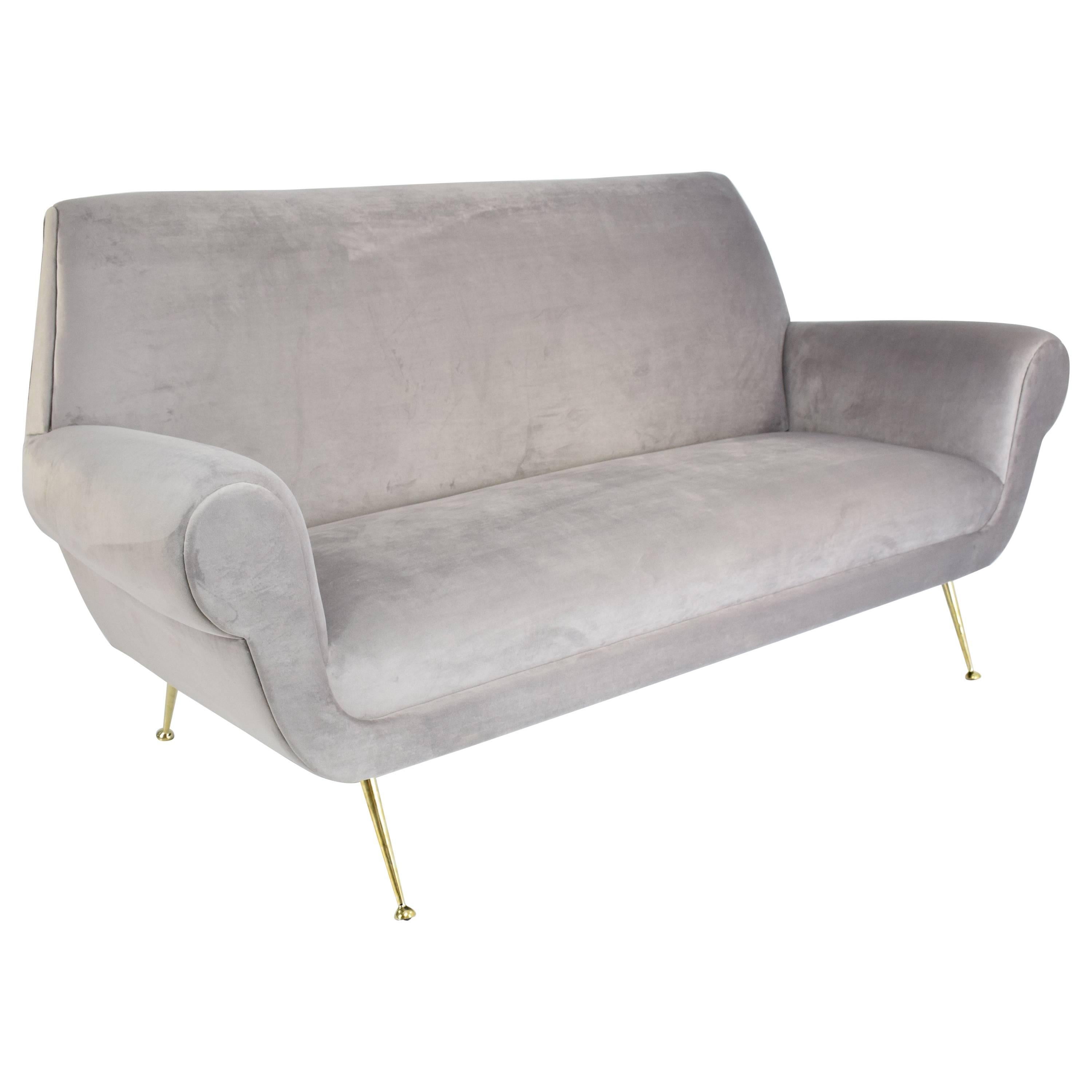 An elegant vintage sofa by Italian midcentury designer Gigi Radice for Minotti expertly restored and reupholstered in soft grey velvet fabric, sitting on splayed and tapered gold polished brass legs with a delicate curved elevated seating effect and