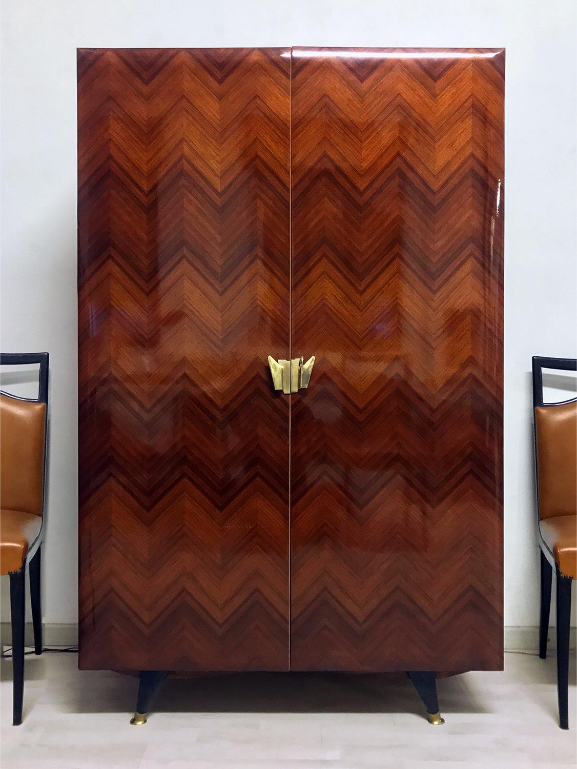 Rare version for this stylish Italian Cabinet 2 doors of the 1950s, attributed to La Permanente Mobili Cantù.
The cabinet is made of a gorgeous lacquered teakwood veneer with marquetry in herringbone pattern, and finished with brass