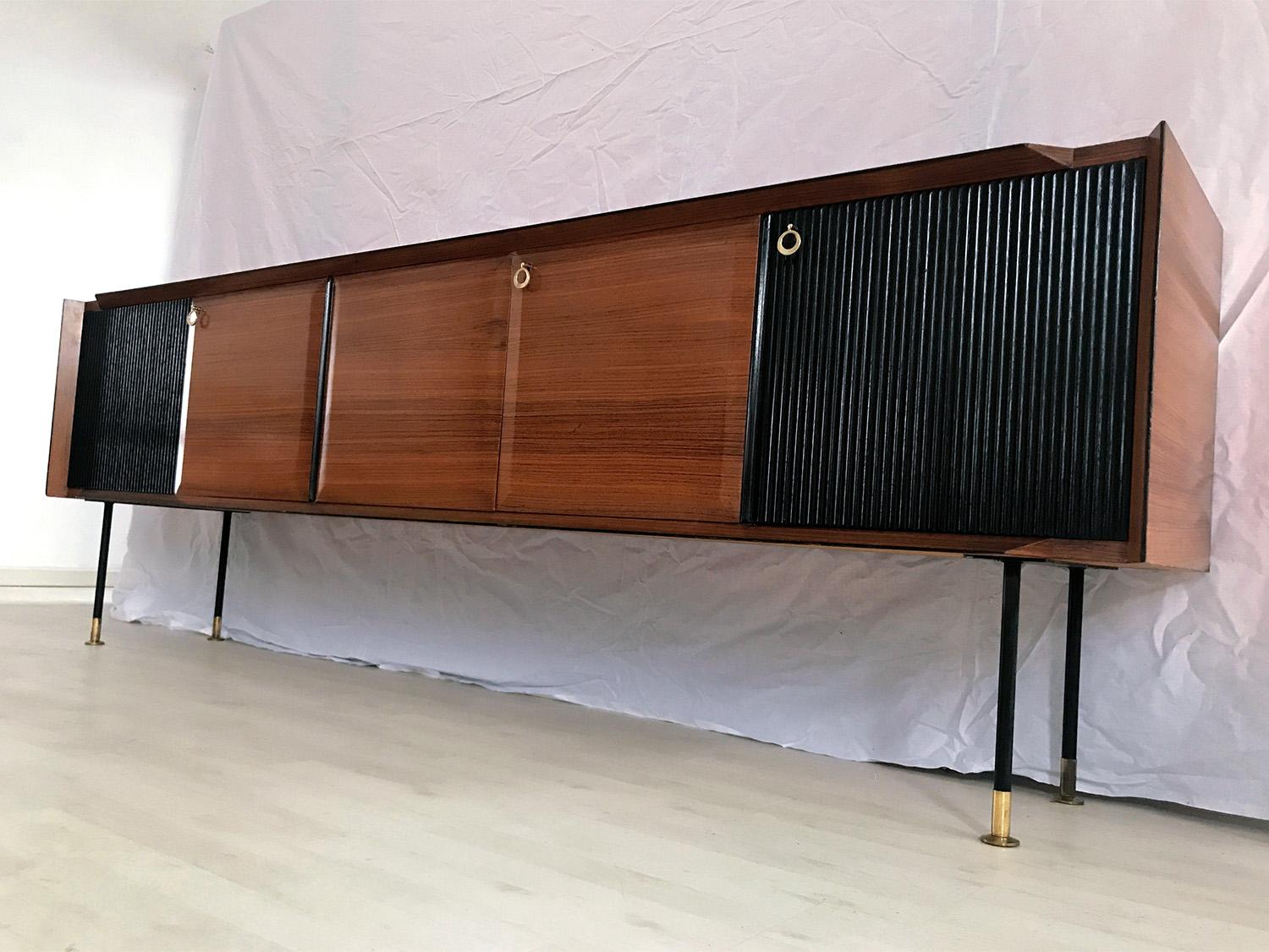 Fantastic Italian sideboard designed by Vittorio Dassi in the 1950s.
The structure is a unique piece composed by a long floating cabinet supported by metal legs finished with brass feet, and many cabinets with doors, partly in teak wood and, on the