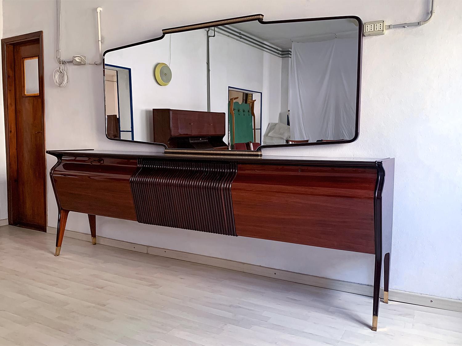 Impressive Sideboard or Buffet with mirror, designed by Osvaldo Borsani in the 1950s.
The cabinet has a long black glass top, and is characterized by a unique shape design given by its amazing curved frontal profile, equipped with three drop-down