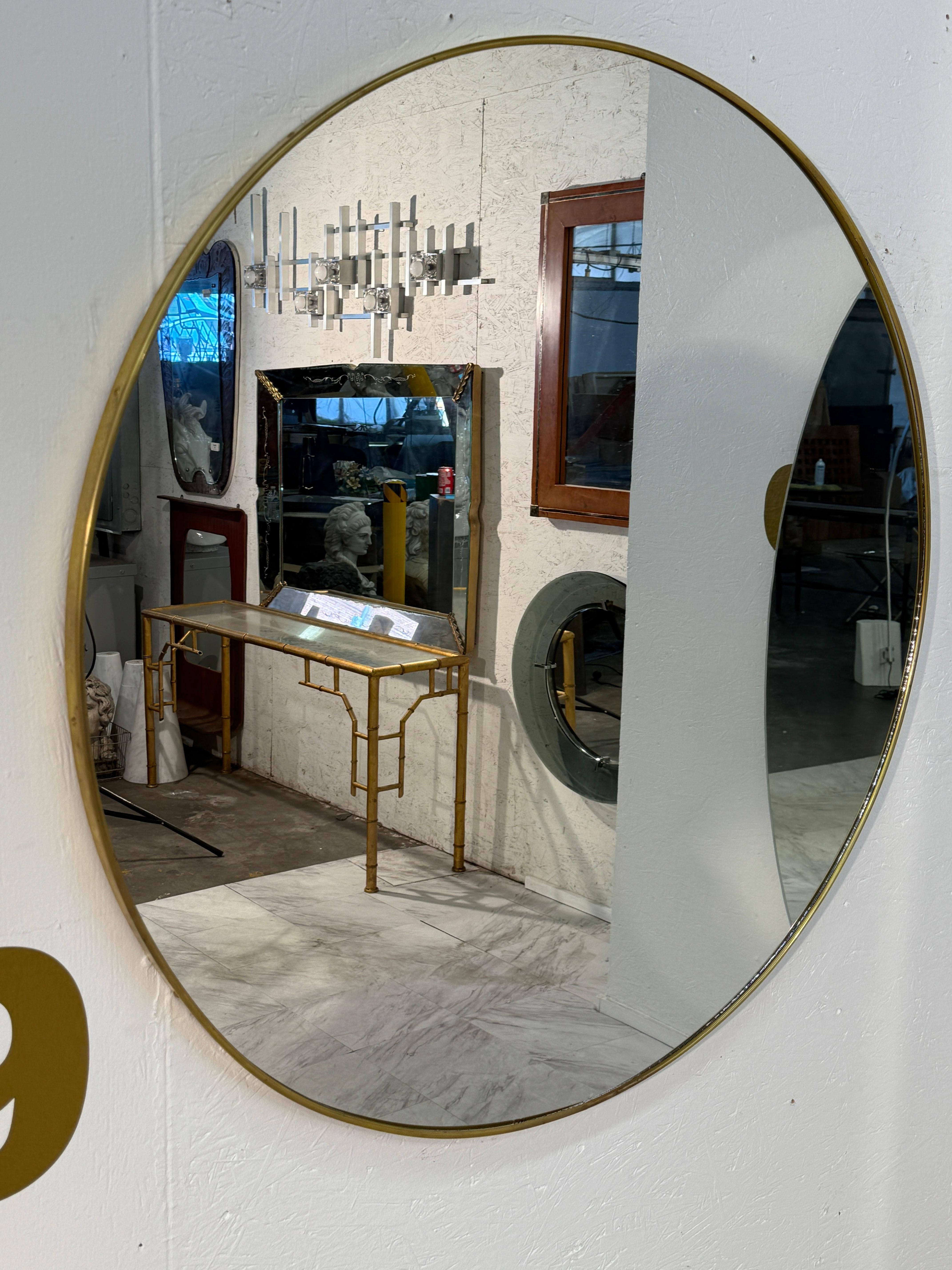 Miroir mural rond italien des années 1950, entouré d'un cadre en laiton élancé à la gracieuse patine vieillie. La simplicité de la forme A reflète l'élégance du design italien du milieu du siècle, où les lignes épurées et les proportions raffinées
