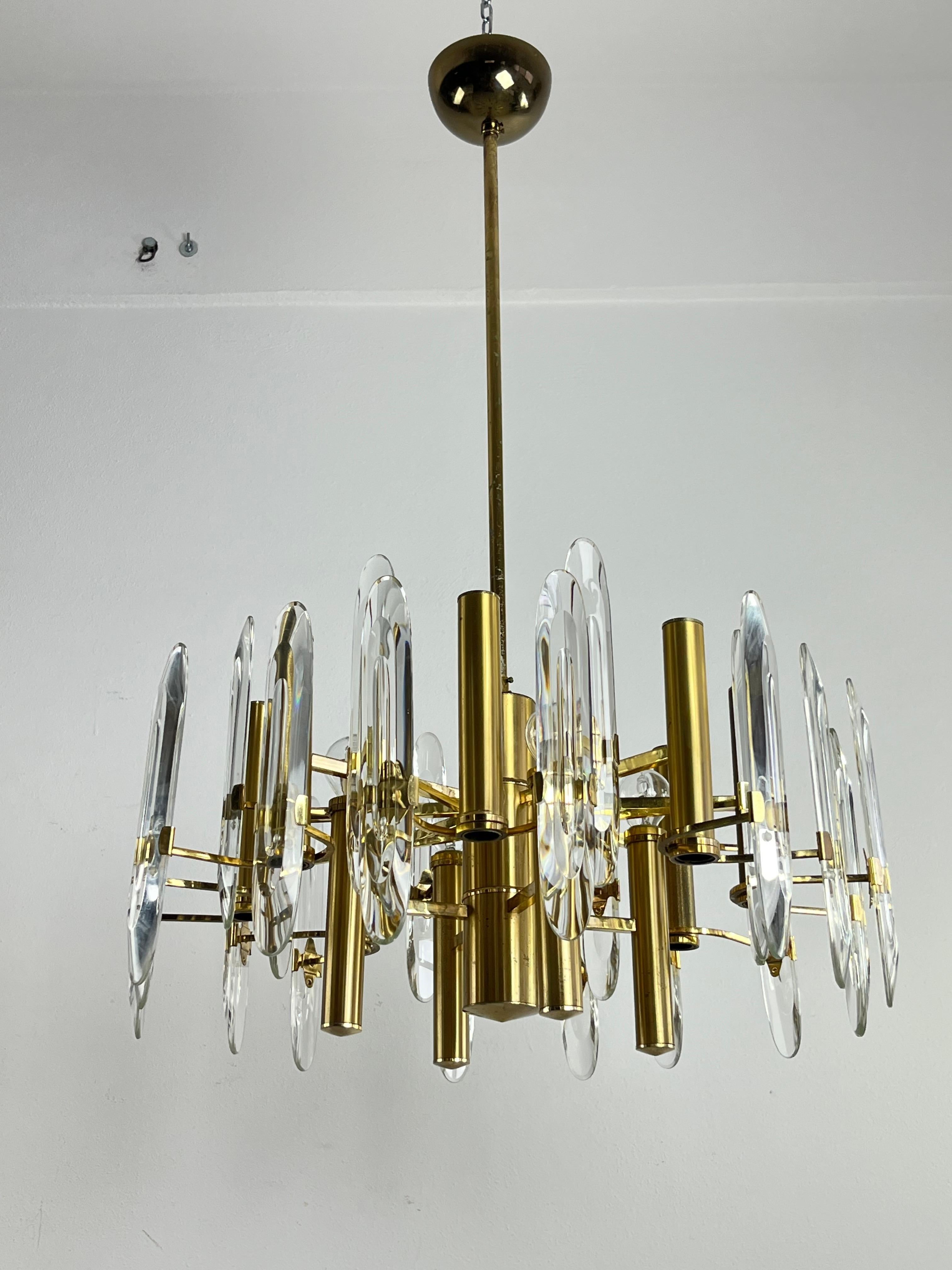 Lampadario italiano Mid-Century Sciolari con 12 prese e 24 prismi di vetro smussato che si irradiano da un cilindro centrale su più livelli, fissati con staffe a braccio singolo e doppio dalla struttura in ottone satinato placcato.
 Piccoli segni di