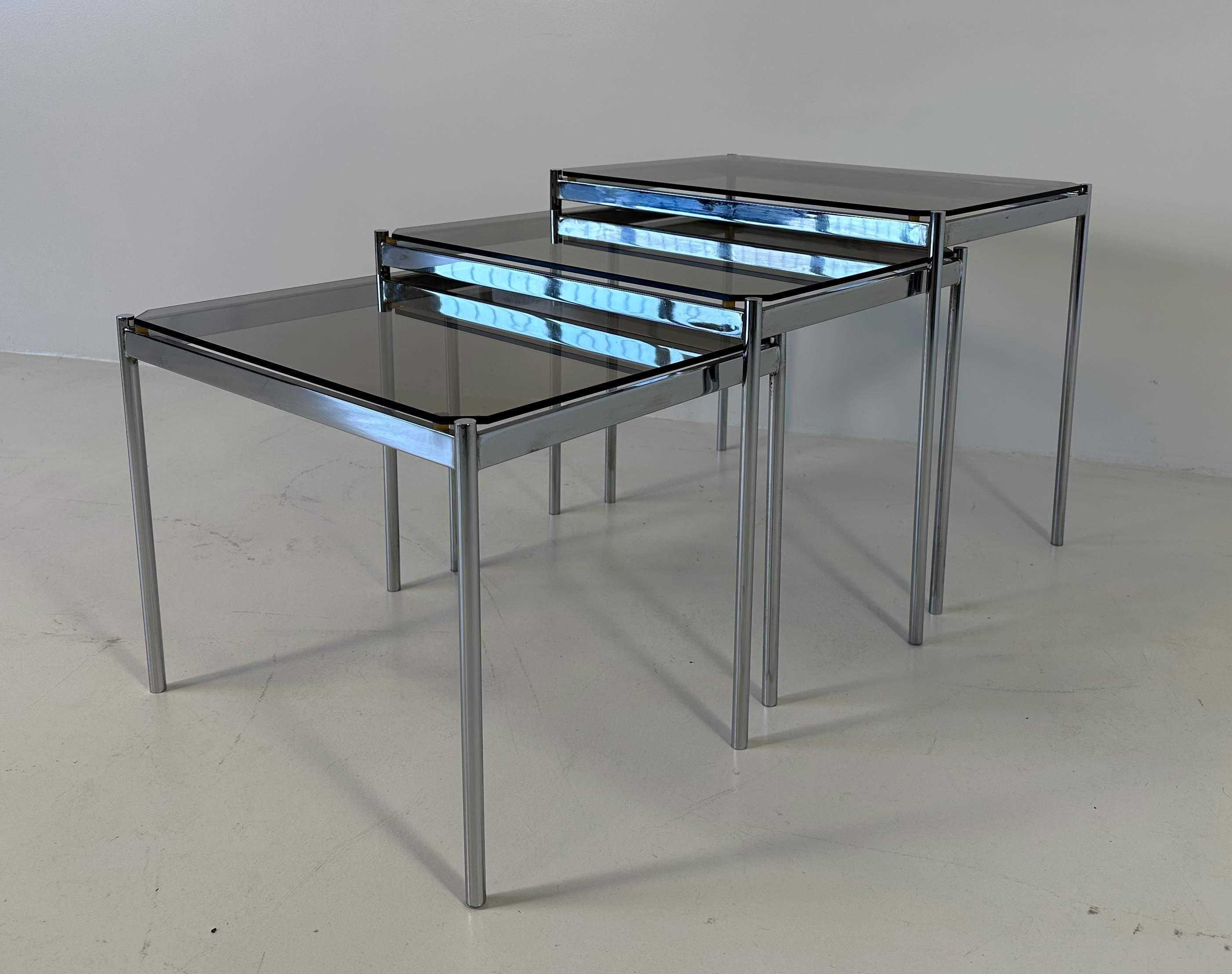 This set of three Mid-Century Modern coffee tables was produced in Italy in the 1970s. 
They are in smoked glass and chromed metal.
In very good vintage conditions.
Measurements: 
largest: 55 cm x 38 cm H 46 cm
medium: 51 cm x 38 cm H 42