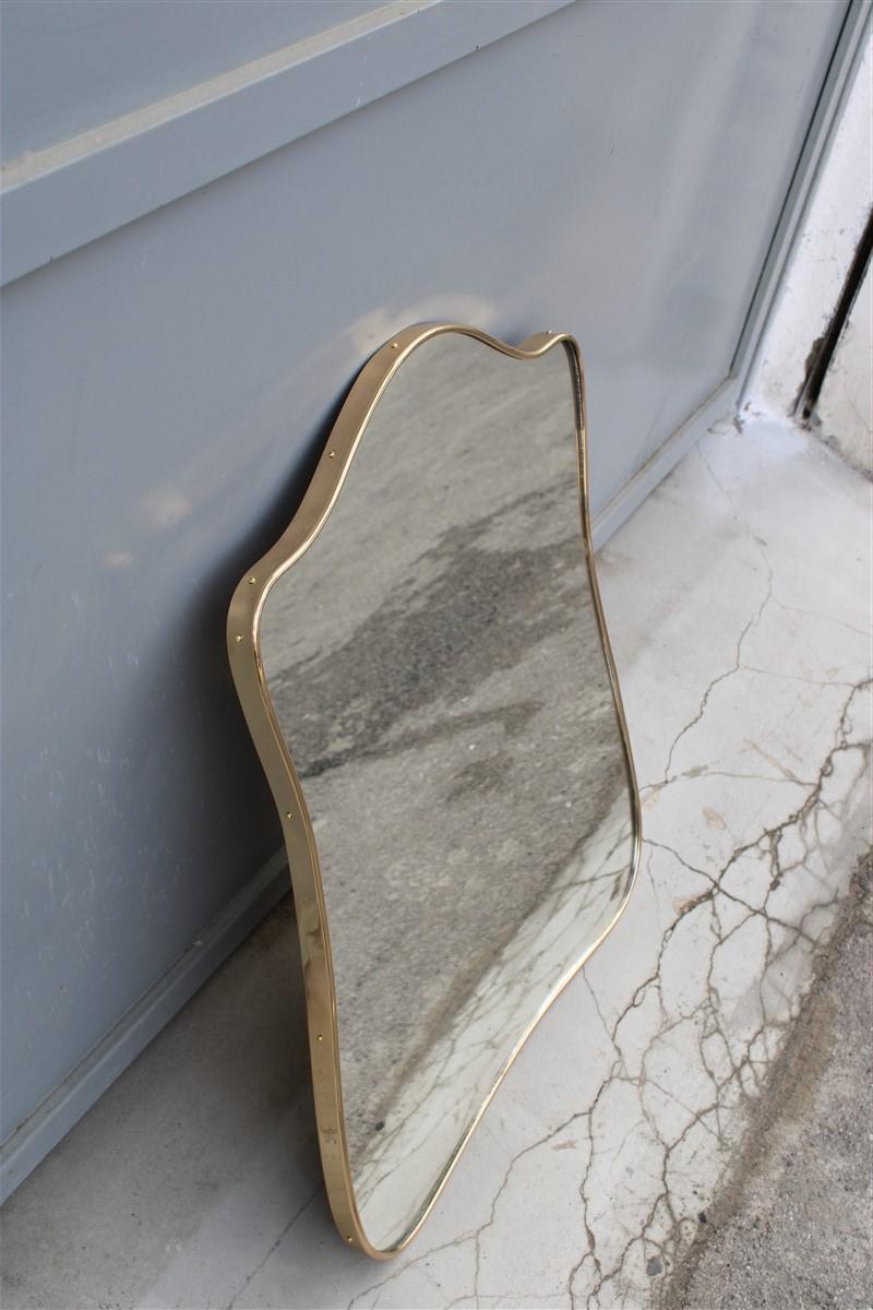 Italian midcentury shaped mirror with elegant gold brass frame.
