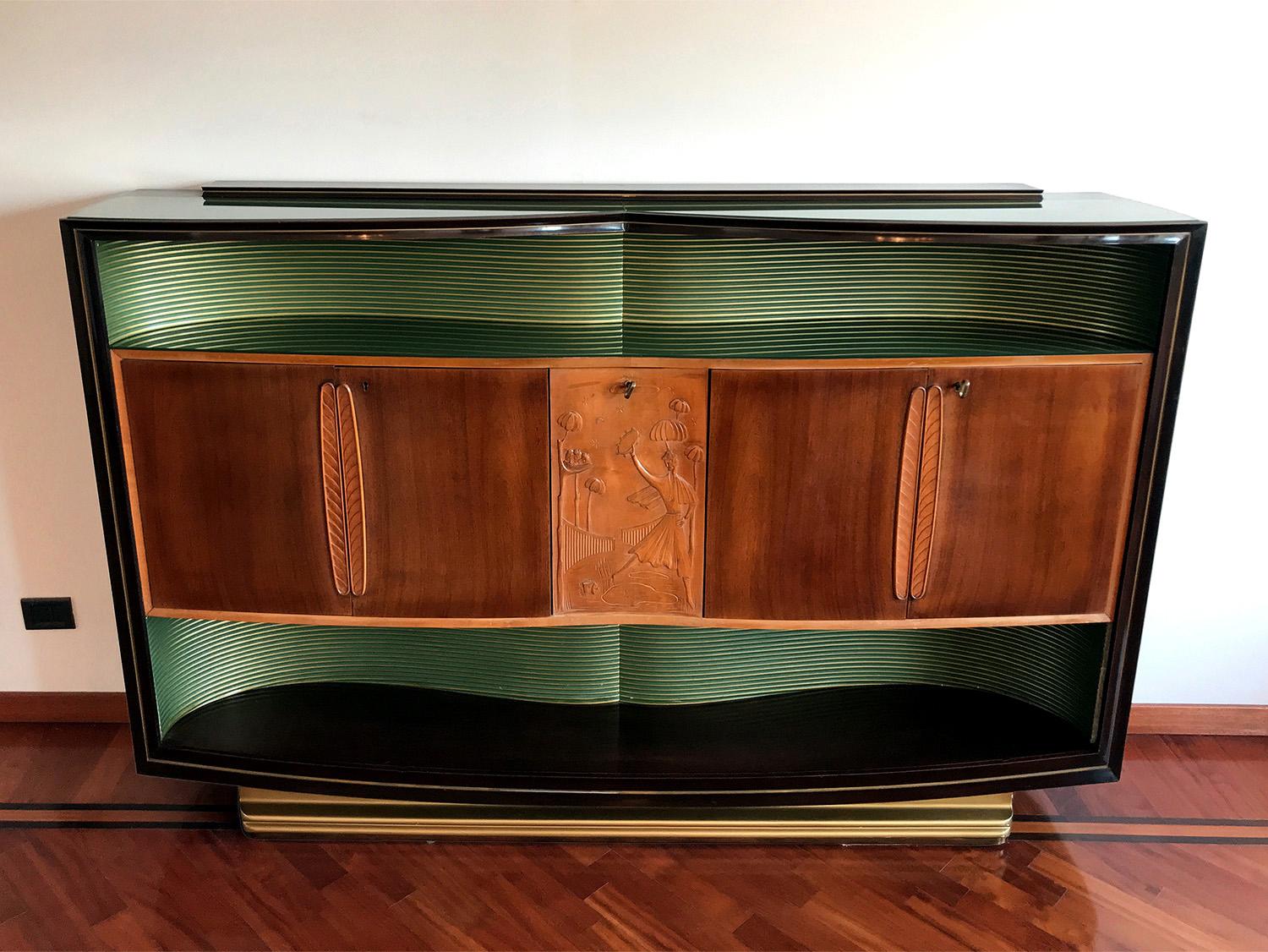 Stunning walnut Sideboard designed by Vittorio Dassi in the 1950s.

It’s finished with two long shaped colored green glass that give it a particularly brightness, one placed on the top plane and the other one inside the hollow, internally crafted of