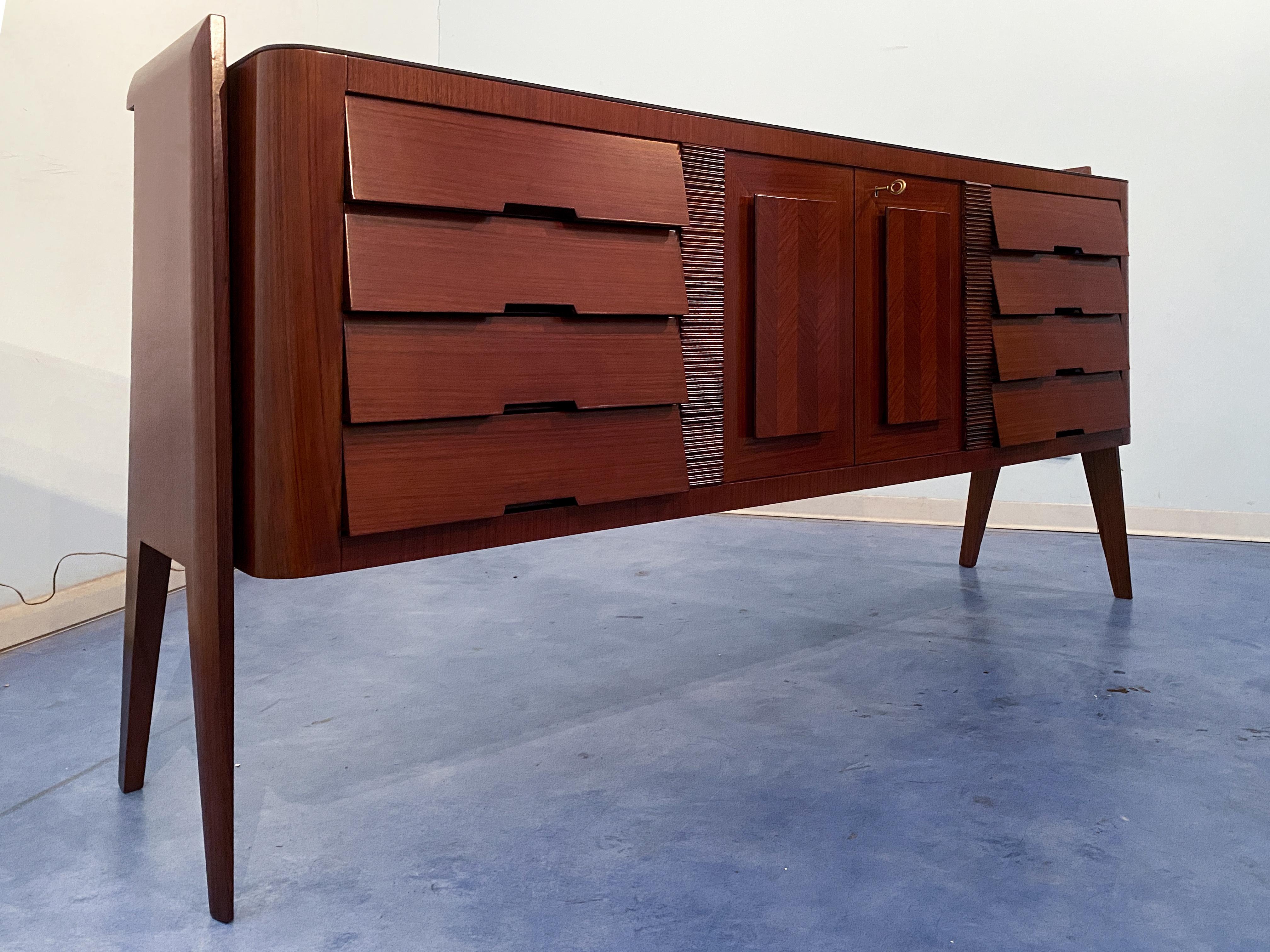 The Italian credenza or sideboard bar by Vittorio Dassi is a refined piece of furniture, featuring a glass top and maple interiors. The front is made up of eight drawers and two doors, and it has been crafted with great attention to execution