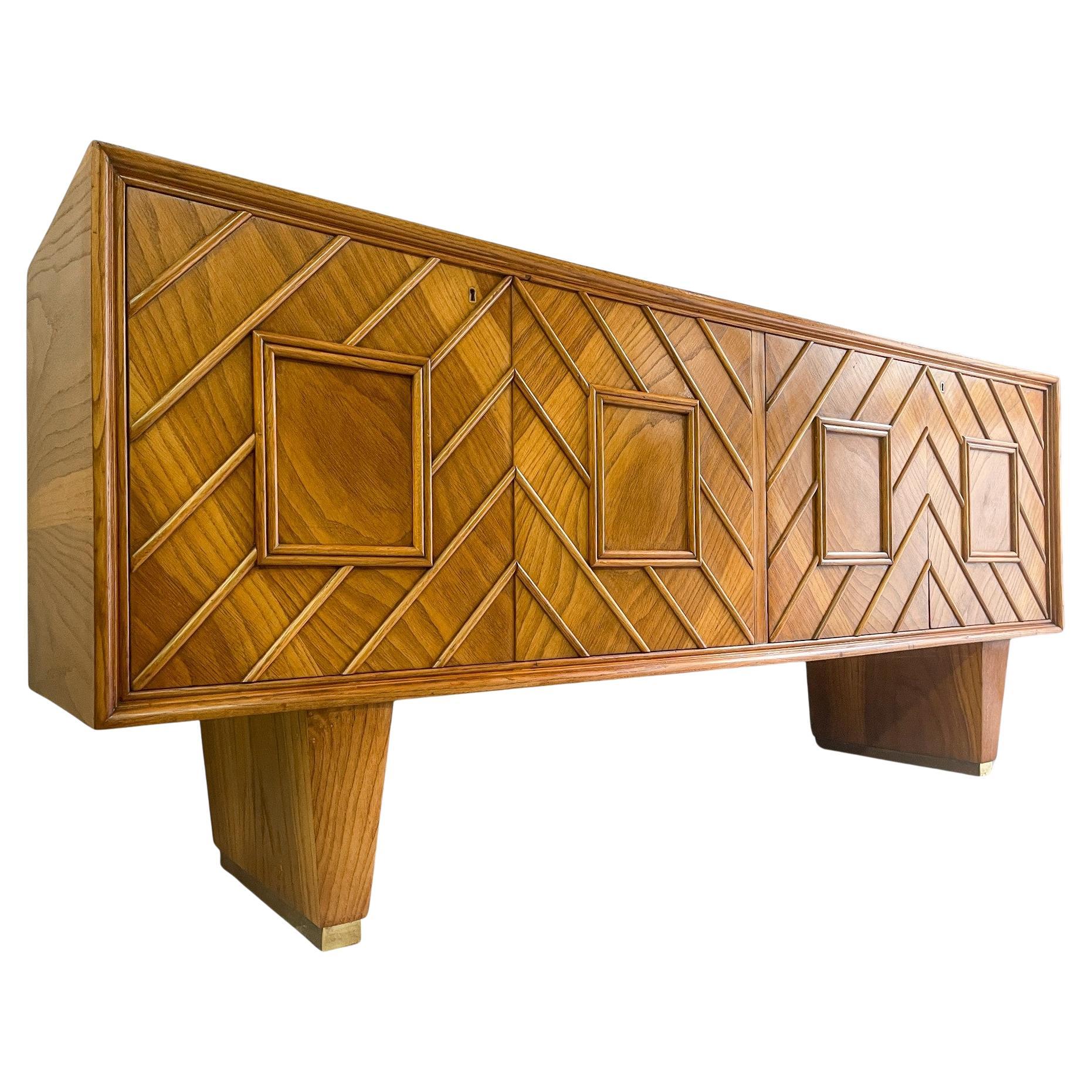 Italian sideboard from the 1950s attributed to Pierluigi Colli, crafted from oak wood with stunning grain. The front features four doors adorned with skillfully positioned raised strips, creating a refined geometric pattern. In the center, a