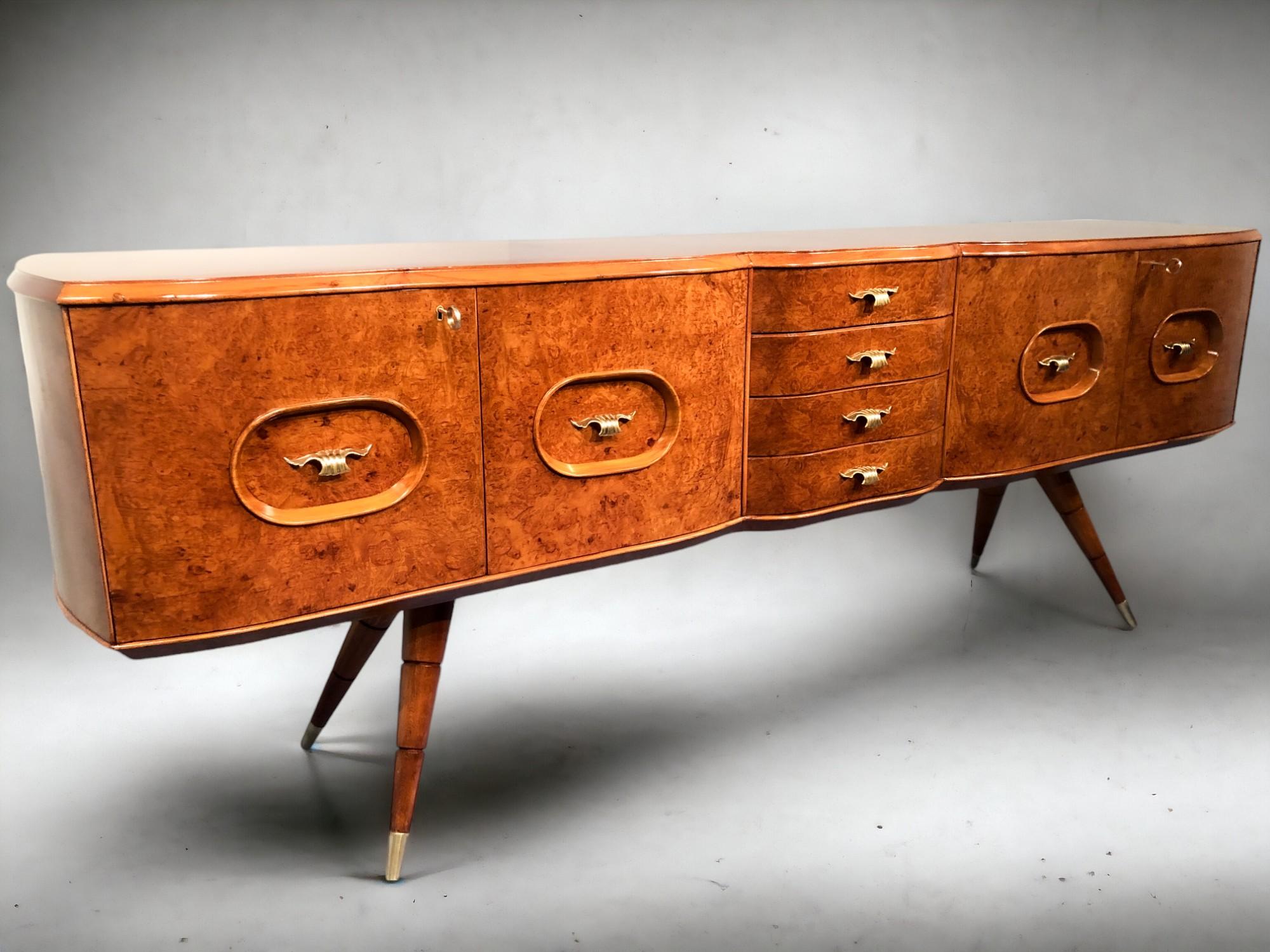 Bellissima credenza italiana di metà secolo realizzata in legno di betulla che le conferisce un caldo color miele. La credenza ha un design frontale sagomato e lati arrotondati. Si distingue anche per i piedi a spillo, che terminano con un sabot in