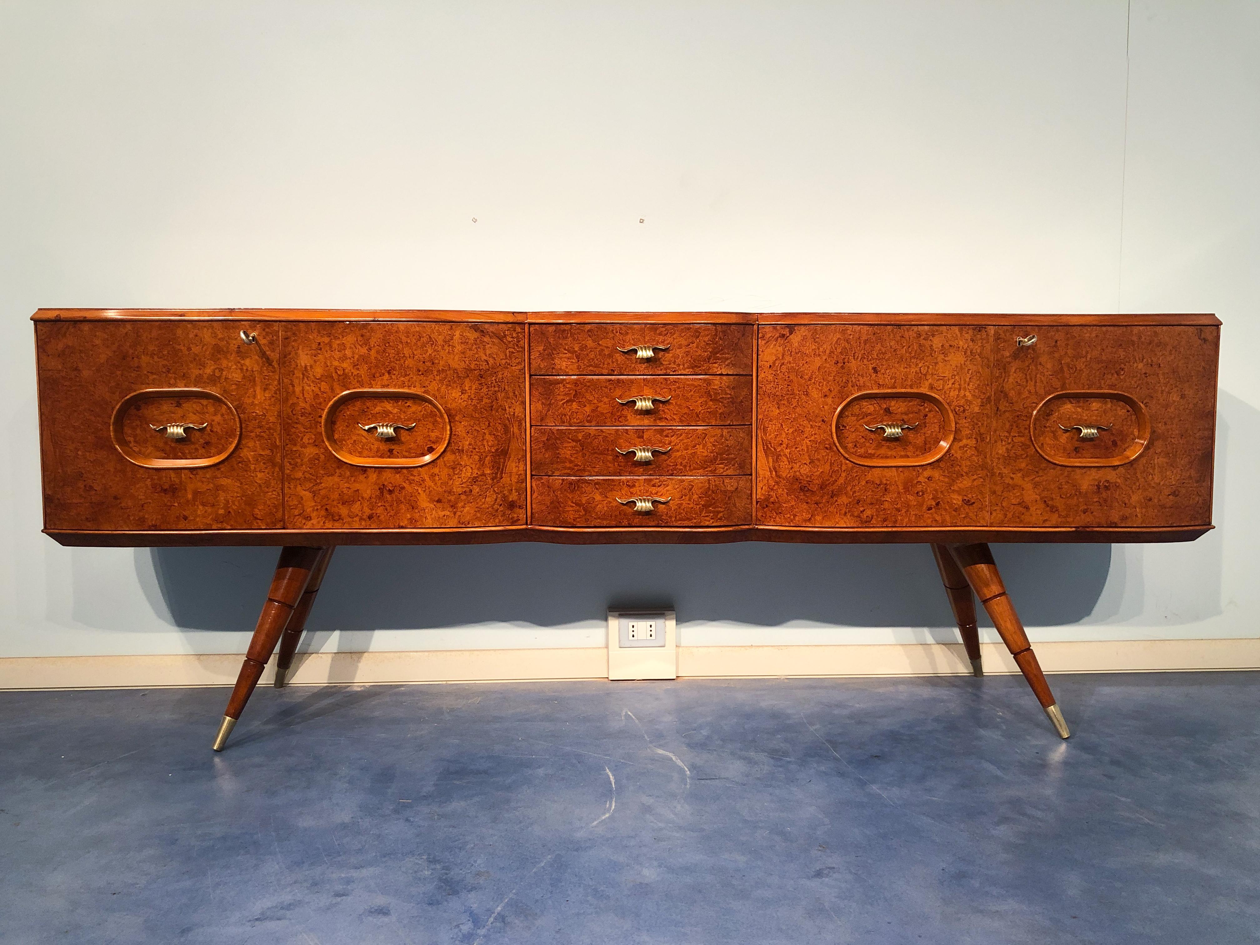 Beautiful Italian mid-century sideboard made of birch wood that gives the sideboard a warm honey color. The sideboard has a shaped front design, as well as rounded sides. It is notable also for the spiked feet, finishing in a brass sabot. The