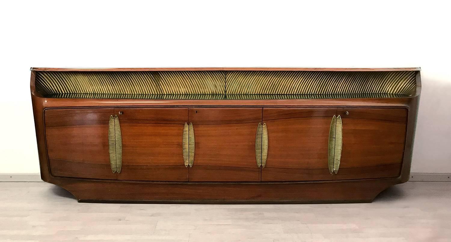 Impressive Italian sideboard or buffet in rosewood, designed by Vittorio Dassi in the 1950s for Palazzi dell’Arte Cantù.
It’s equipped with five doors decorated with gilded brass profiles, the four side ones hiding shelves and the middle one with
