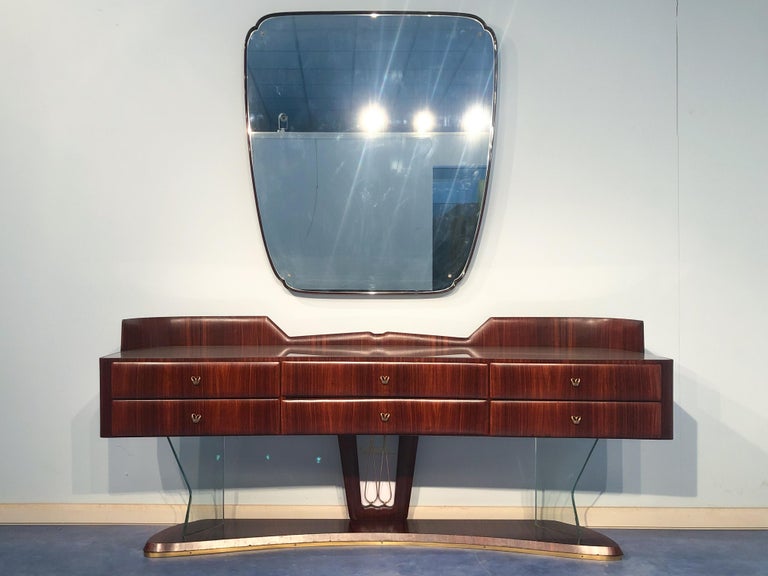 Italian mid-century sideboard in rosewood produced by Vittorio Dassi in the 1950s. This sideboard has excellent manufacturing aspects, noticeable from the arched line, hard transparent glass support, elegant brass handles, and a back finish. Those