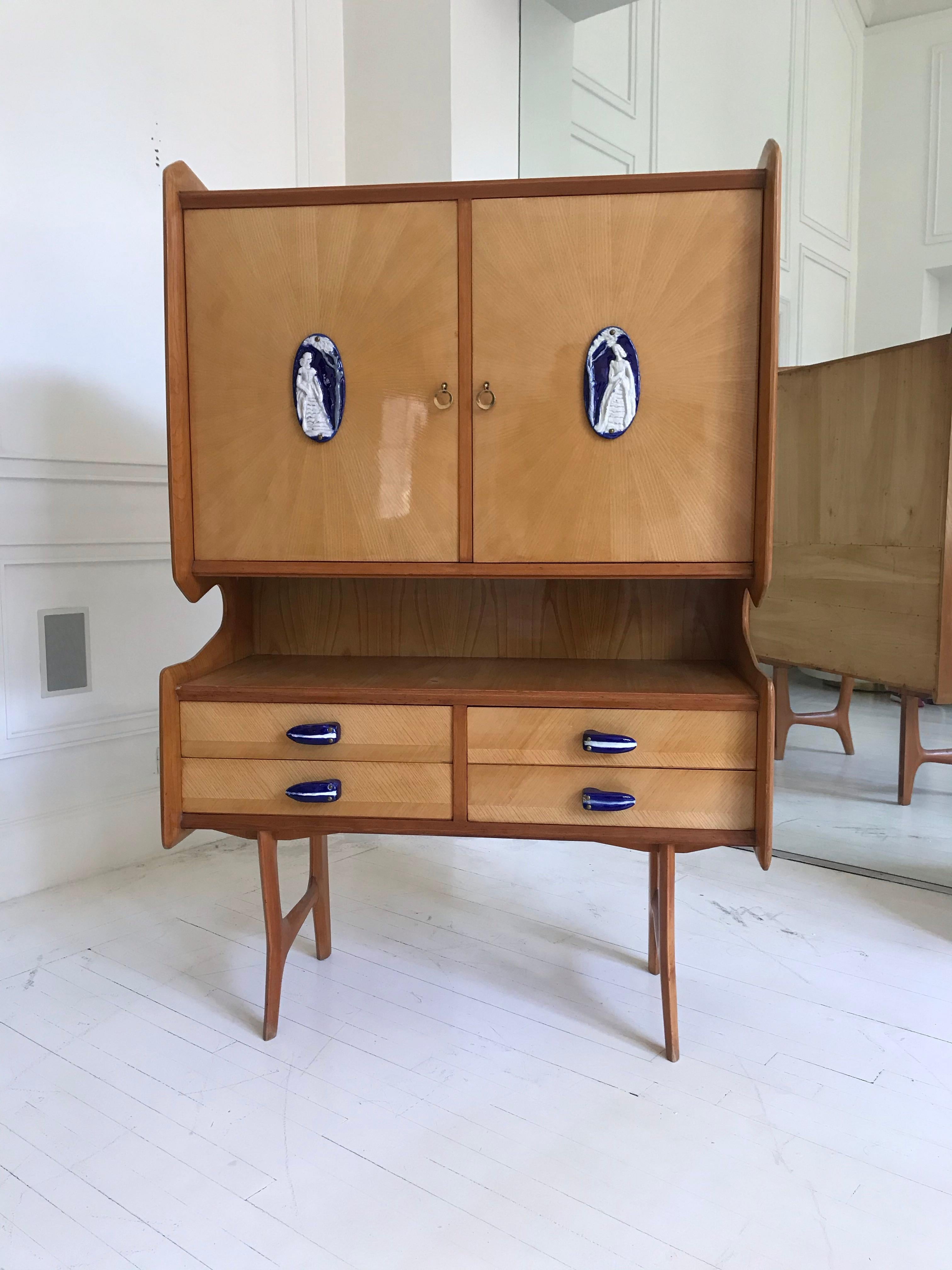 Italian vintage cabinet in the manner of Ico Parisi featuring ceramic handles, brass pulls and cartouche decorations by Richard Ginori. Constructed of sycamore wood with two doors and four drawers.