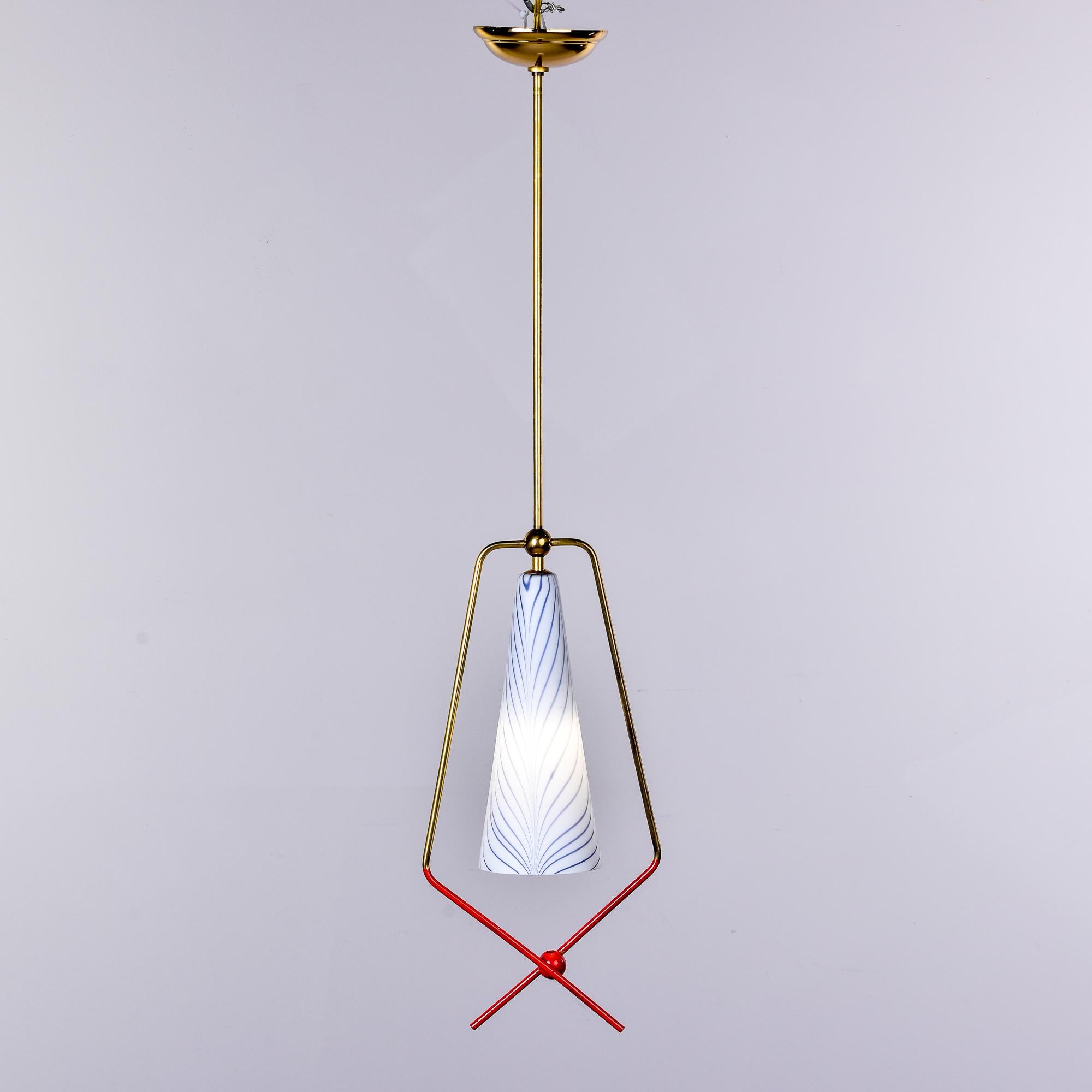 Found in Italy, this single light pendant fixture dates from the late 1950s / early 1960s. Polished brass canopy and slender support rod with a white glass shade framed by a brass surround with red finish on the ends. Unknown maker. New wiring for