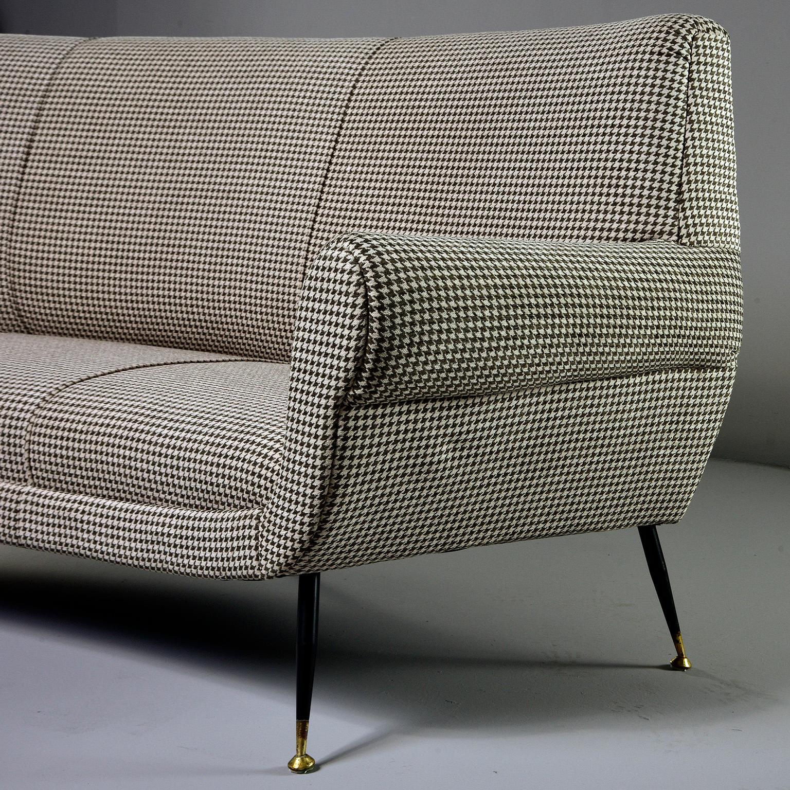 Sofa / settee designed by Gigi Radice for Italian maker Minotti, circa late 1950s. This iconic piece features curvy, midcentury Italian lines, narrow metal legs with black enamel finish and brass feet and new upholstery. Fabric is a short napped