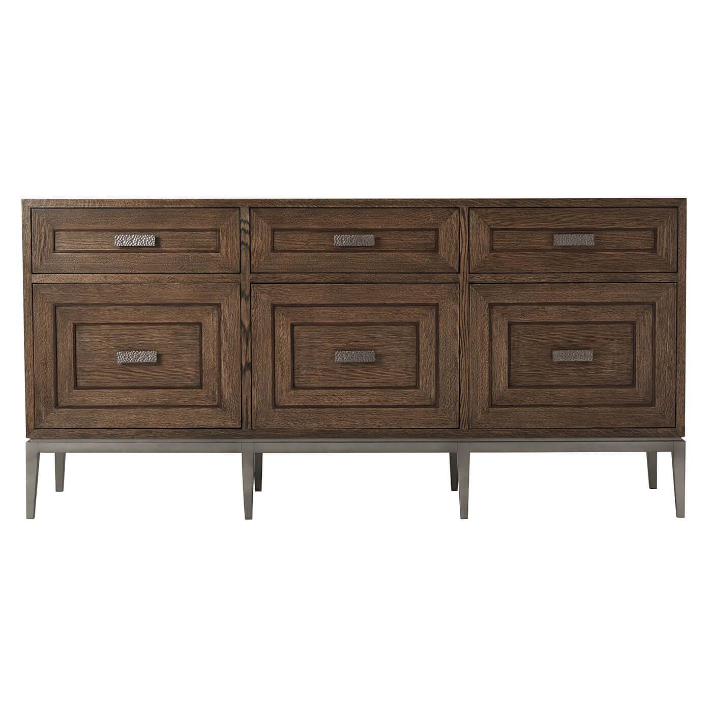 Italian midcentury style sideboard with a brushed oak charter is finish with three frieze drawers with relief inlaid angular centric lines, three similar cabinet doors below having hammered metal handles with a matte tungsten finish and raised on