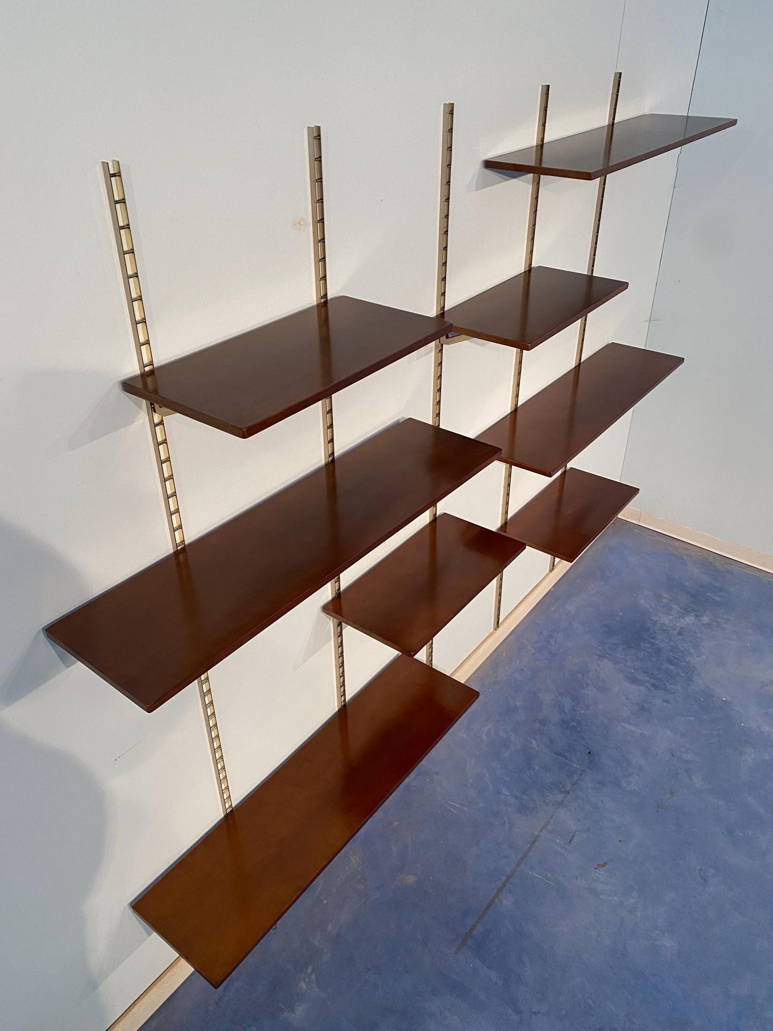 An eye-catching mid-century Italian wall unit or bookcase made from gilded metal and walnut shelves that can be adapted to any setting due to its lightness and refinement. The bookcase is composed of N.5 track supports, N.16 shelves brackets, N.4