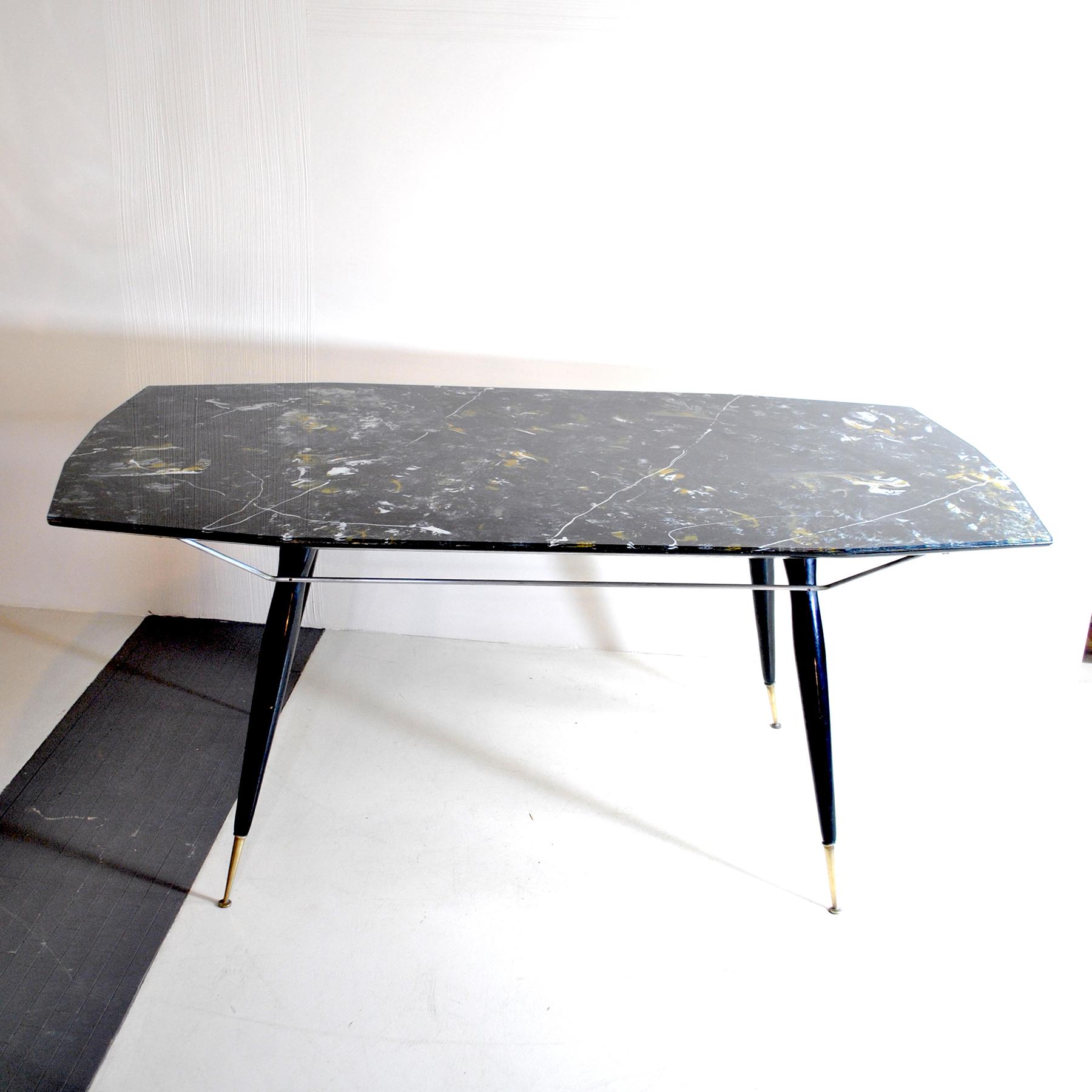 Table avec pieds en bois et borne en laiton, sur le dessus en verre restro moulé représentant du marbre noir de Carrare.
Bien qu'elle ne soit attribuée à aucun designer de l'époque, cette table présente de nombreuses caractéristiques qui laissent