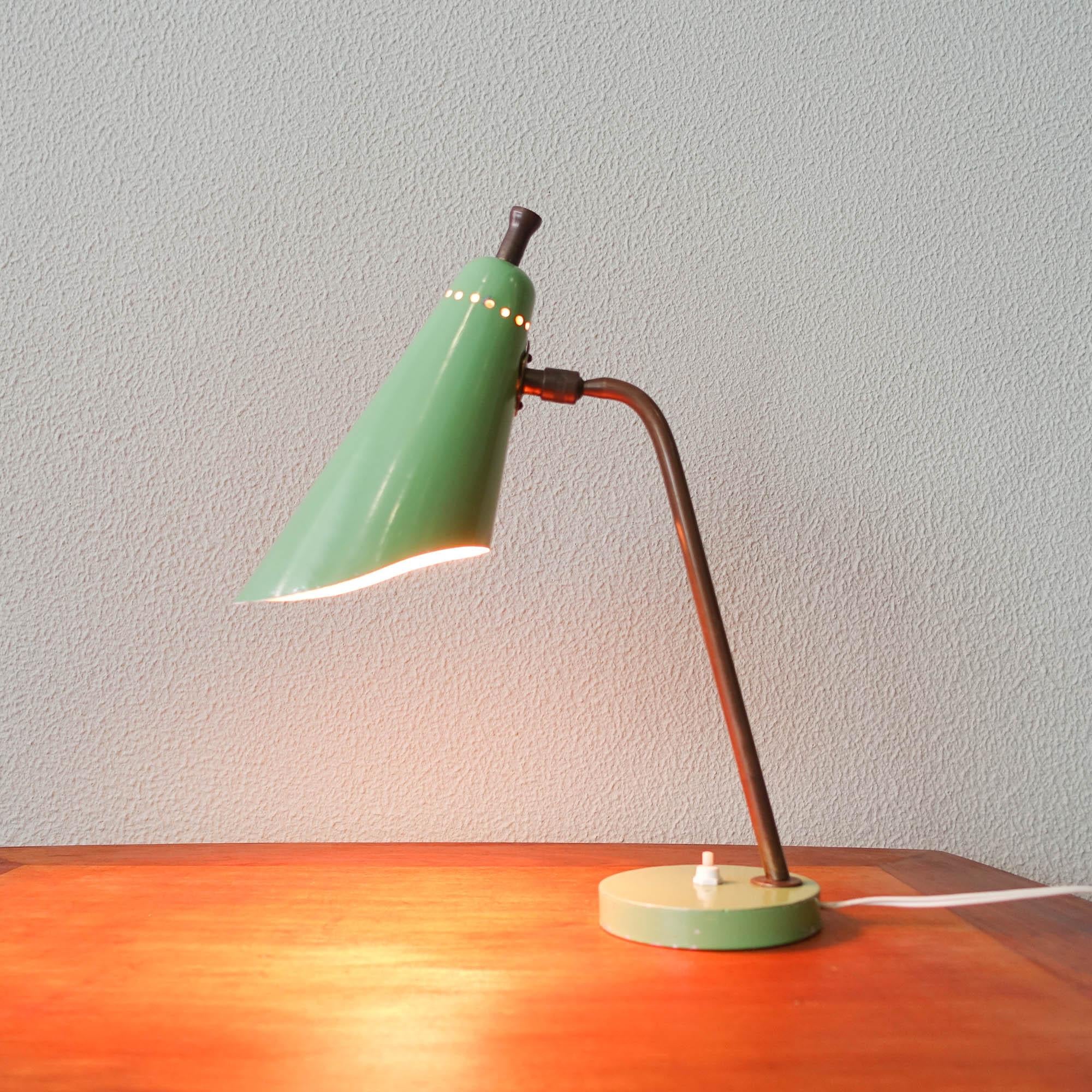 This Mid-century table lamp was designed and produced in Italy, during the 1950s. It has a light green base where a brass curved rod is attached. With a light green painted lampshade, off white painted inside and a brass rod on top. It is in the
