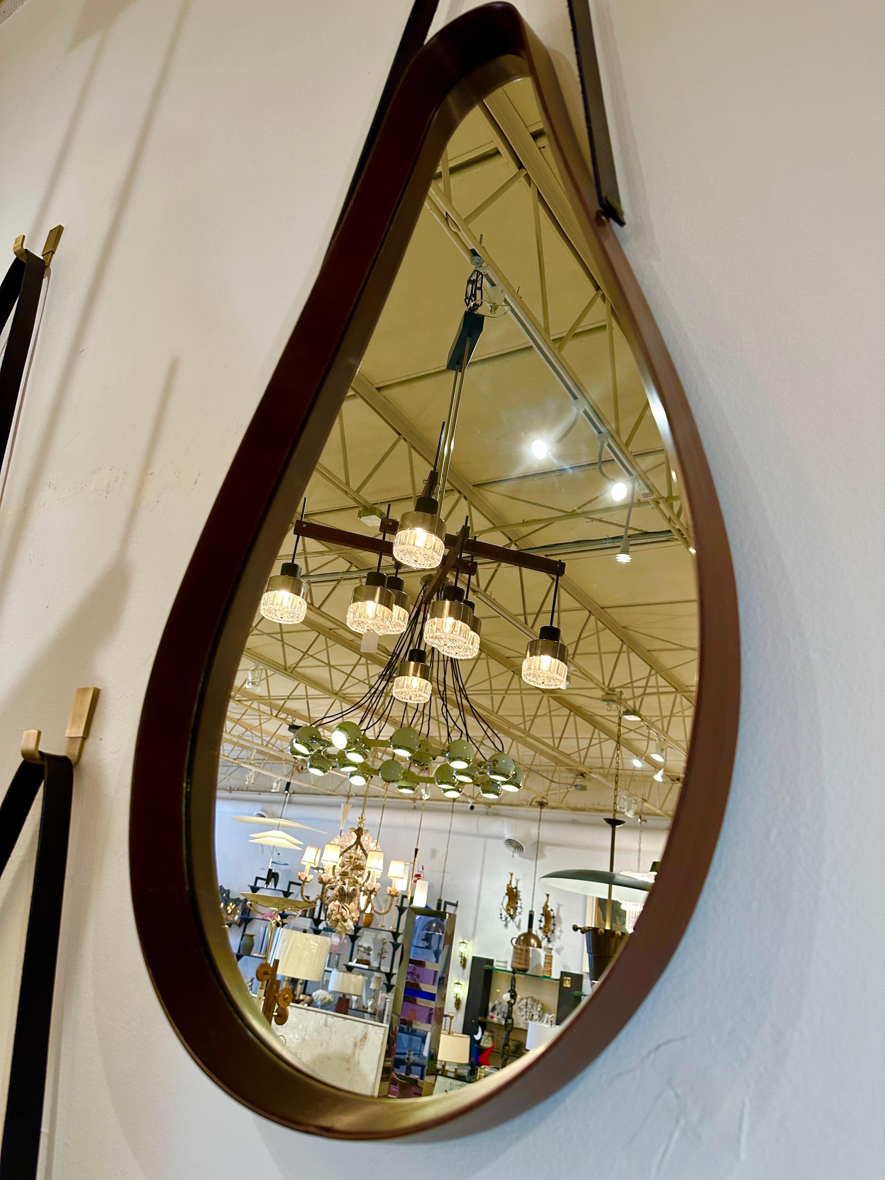 This wonderful Classic Italian midcentury walnut frame mirror in a tear-drop style with a thick leather hanging strap and custom brass hook (included). This beauty is part of a group of THREE (3) that we acquired in our travels. They are sold