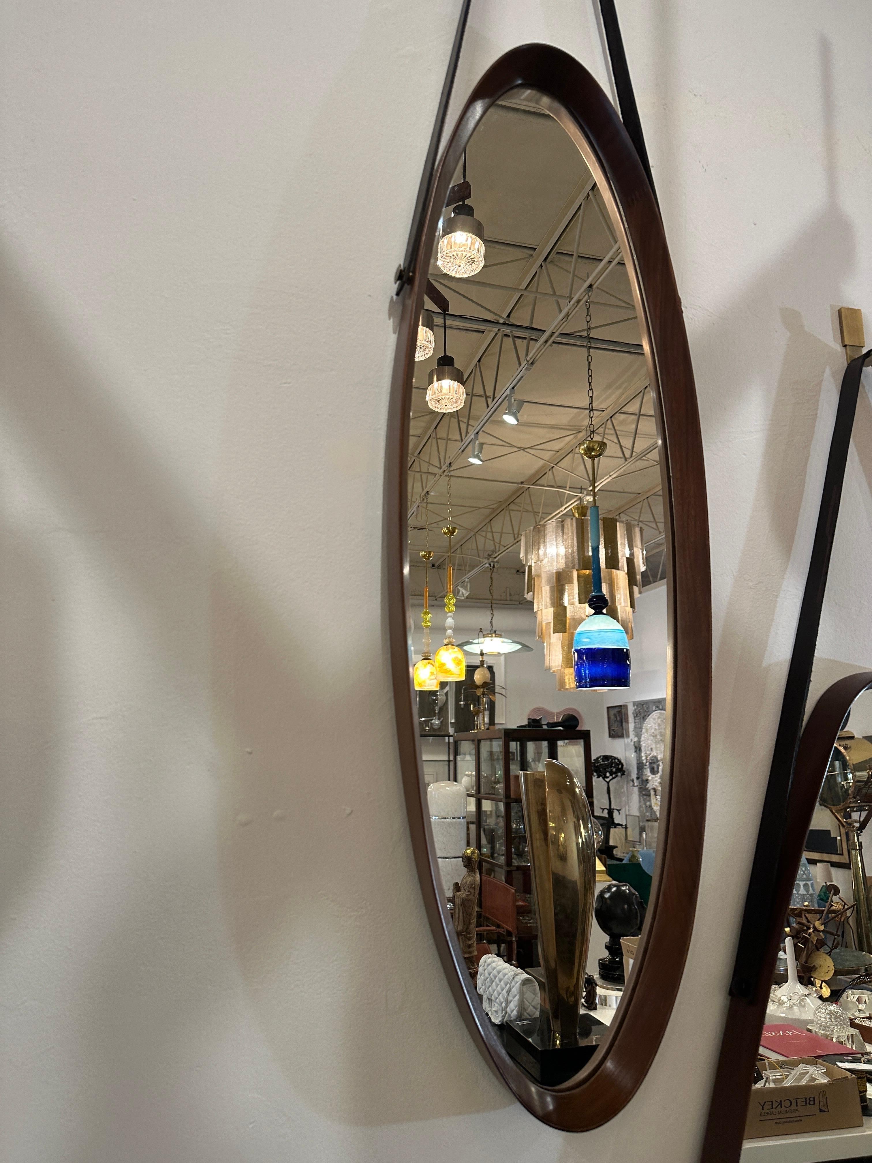 This wonderful Classic Italian midcentury walnut frame mirror in an oval design with a thick leather hanging strap and custom brass hook (included). This beauty is part of a group of THREE (3) that we acquired in our travels. They are sold