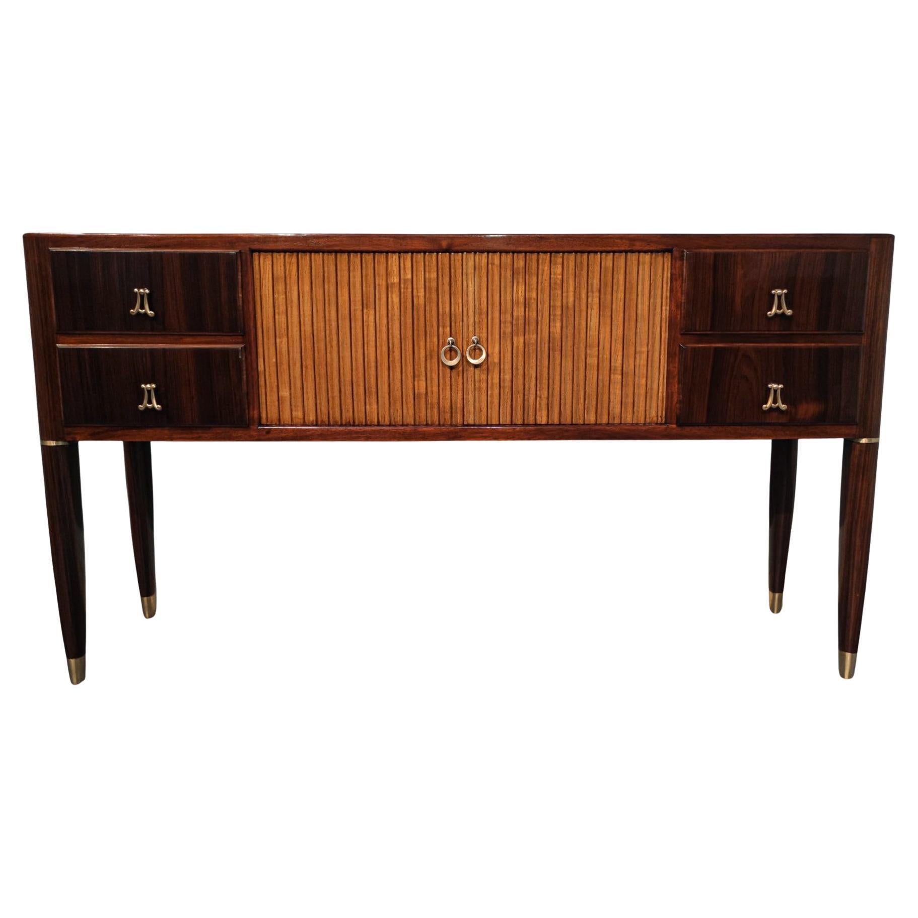 Aparador italiano de mediados de siglo en teca, atribuido a Paolo Buffa, de la década de 1950. Pieza muy elegante y de gran calidad ejecutiva. Tiene un diseño realmente refinado con muchos detalles como patas con adornos de latón o tiradores de