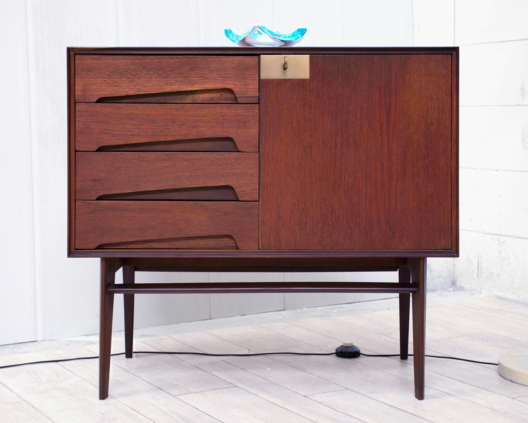 This amazing small sideboard is original of the 1950s, its structure is made in gorgeous material like warm teak wood veneered, equipped with four drawers on the left side and openable door on the right side, finished with brass detail.

It’s in