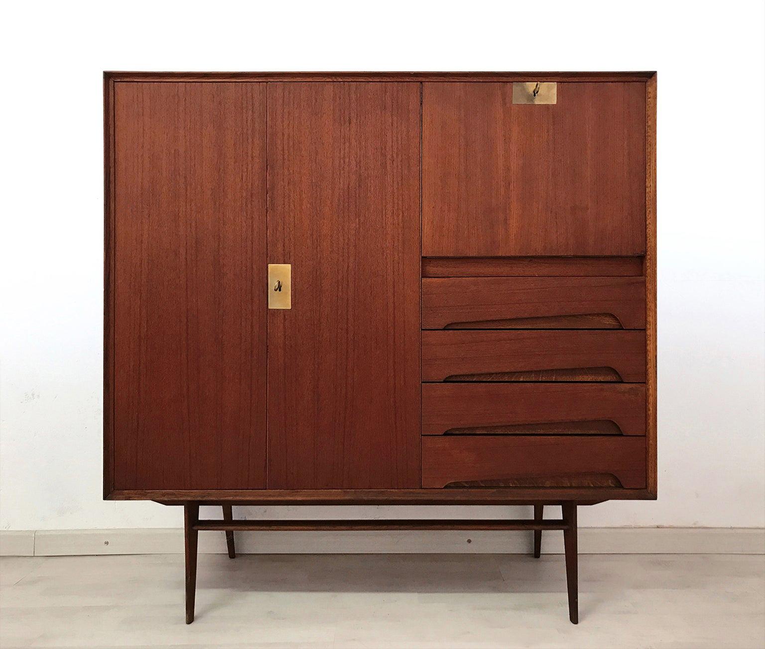 This sideboard has been crafted with a gorgeous material like as warm teakwood, finished with brass details, and its uniqueness is given by the presence of a drop-leaf door on the right side, that makes it available as a secretaire.
Its doors and