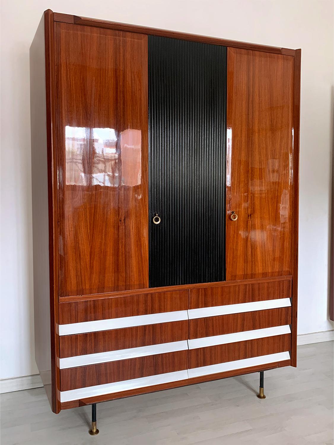 Stunning Italian Armoire 3-door and 6 drawers, well designed by Vittorio Dassi in the 1950s.

The cabinet is made of a beautiful lacquered teakwood, supported by black metal legs finished with adjustable brass feet.
The central ebonized door is