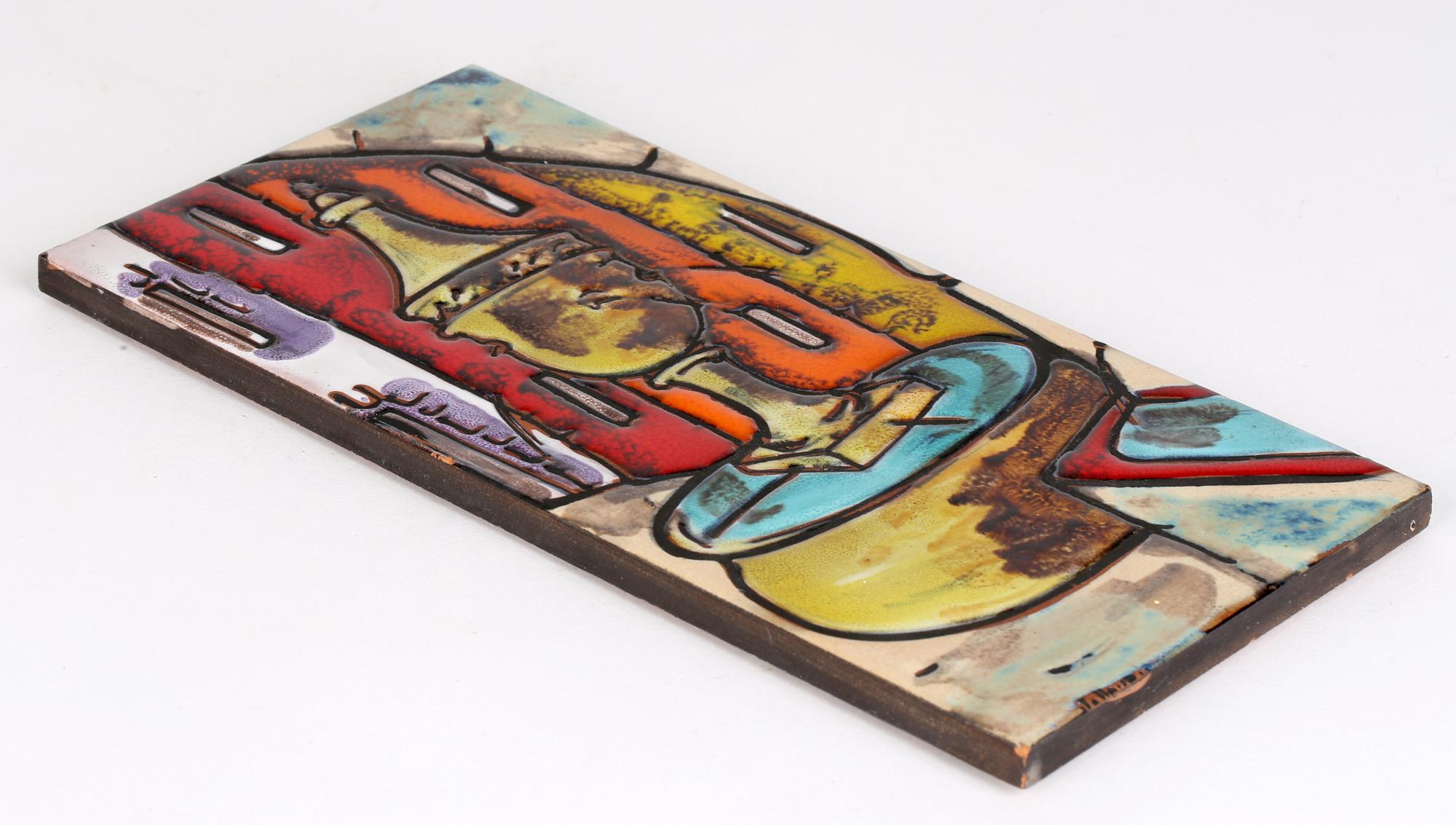 An Italian mid-century hand crafted signed terracotta tile decorated with a street scene with a fountain in colored enamels. The tile of tall rectangular shape has an incised outline filled in matt black with the sections in between hand-painted in