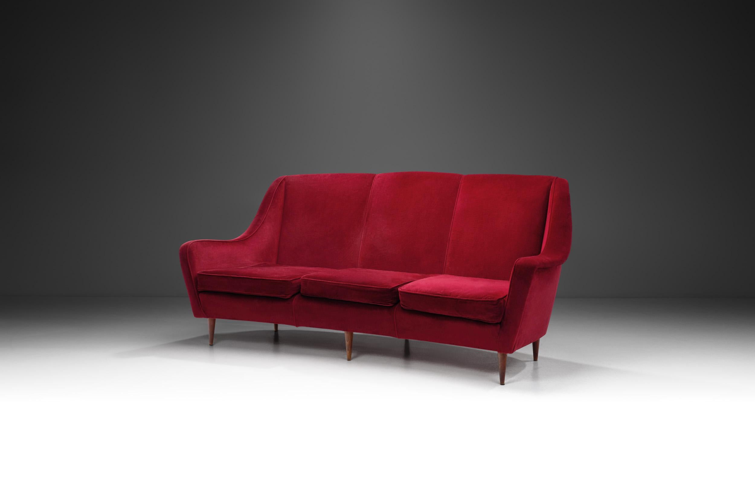 Dieses italienische Sofa aus den 1950er Jahren strahlt zeitlosen Charme und Eleganz aus. Dieses Dreisitzer-Sofa ist mit rotem Samt überzogen und zeigt, warum italienische Möbel aus der Mitte des Jahrhunderts nach wie vor attraktiv sind. Die Möbel
