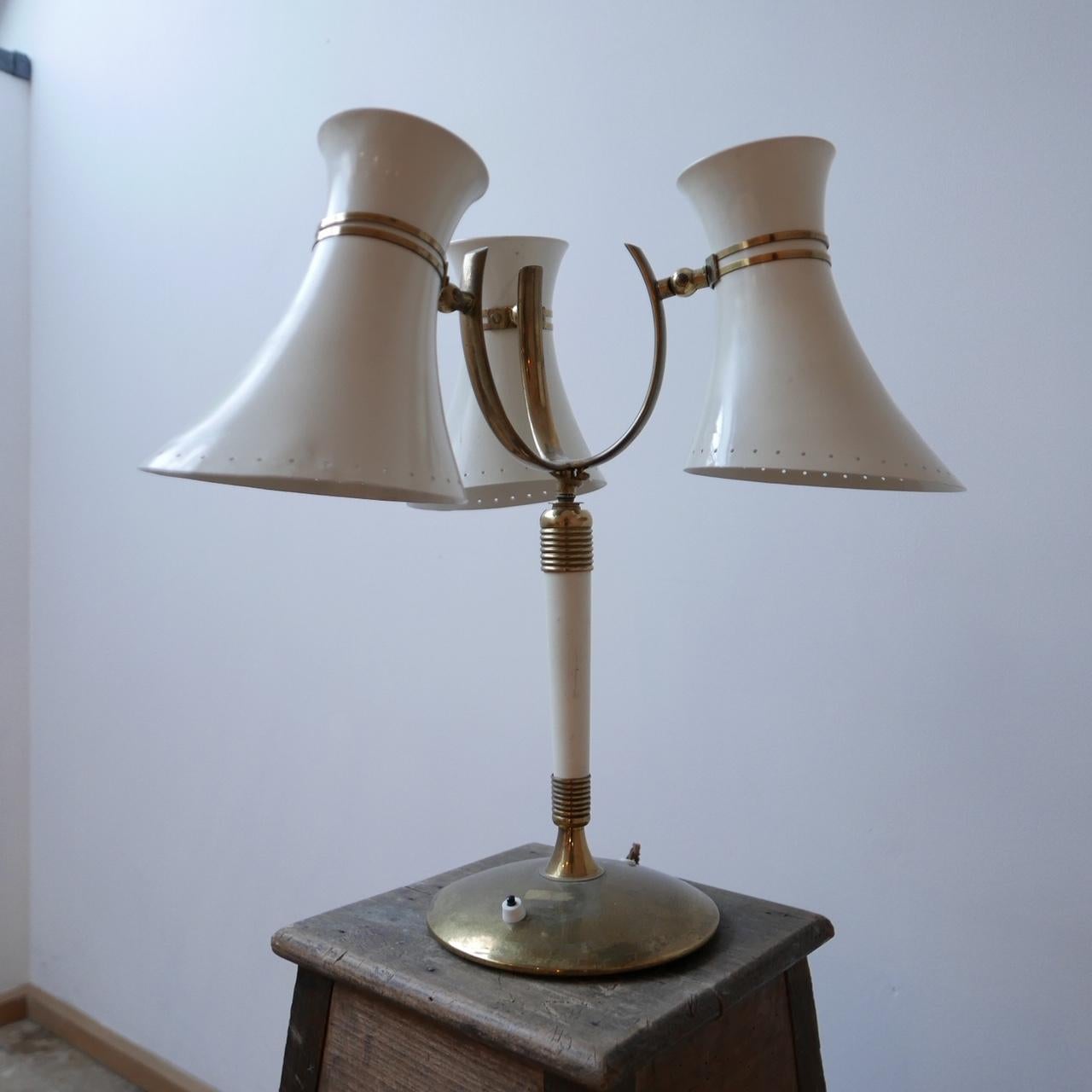 A midcentury brass and steel shade three light table lamp.

Italy, circa 1960s.

Adjustable shade heads which can change how the light is directed.

Dimensions: 50 H x 47 W x 45 D in cm.