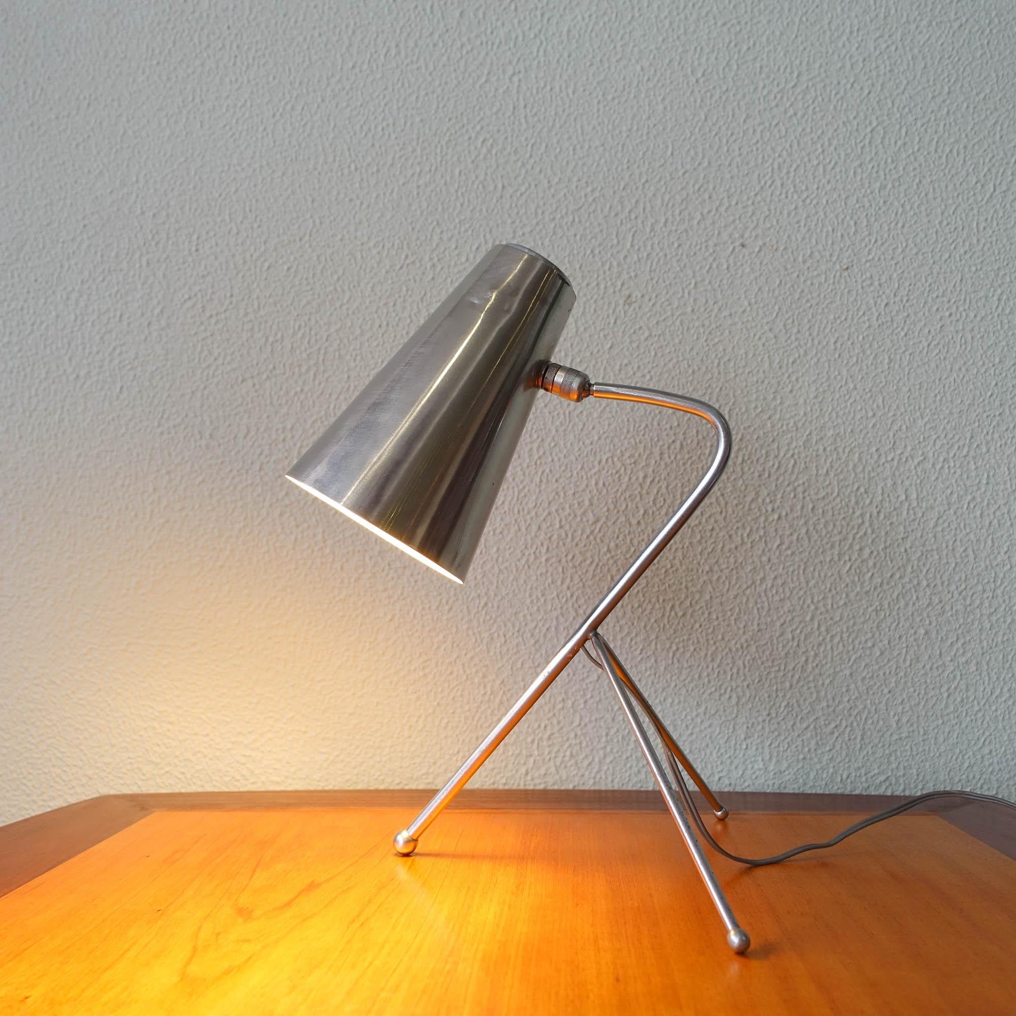 This desk lamp was designed and produced in Italy, during the 1950's. It has an elegant design with a tripod base and an aluminum lamp shade. The lamp shade is articulated so you can position it in various ways. In original and good vintage