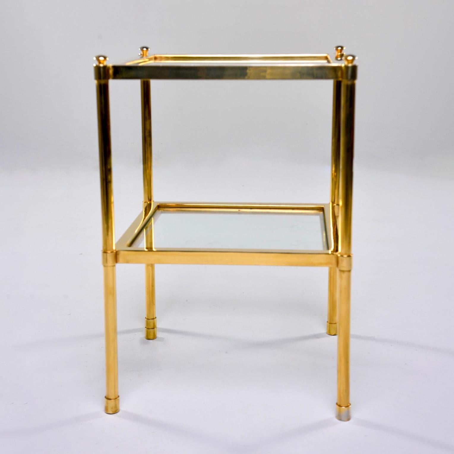 Italian side table has a brass frame with lower shelf and tabletop of clear glass, circa 1970s. Unknown maker. Very good vintage condition with scattered surface wear to glass and brass.