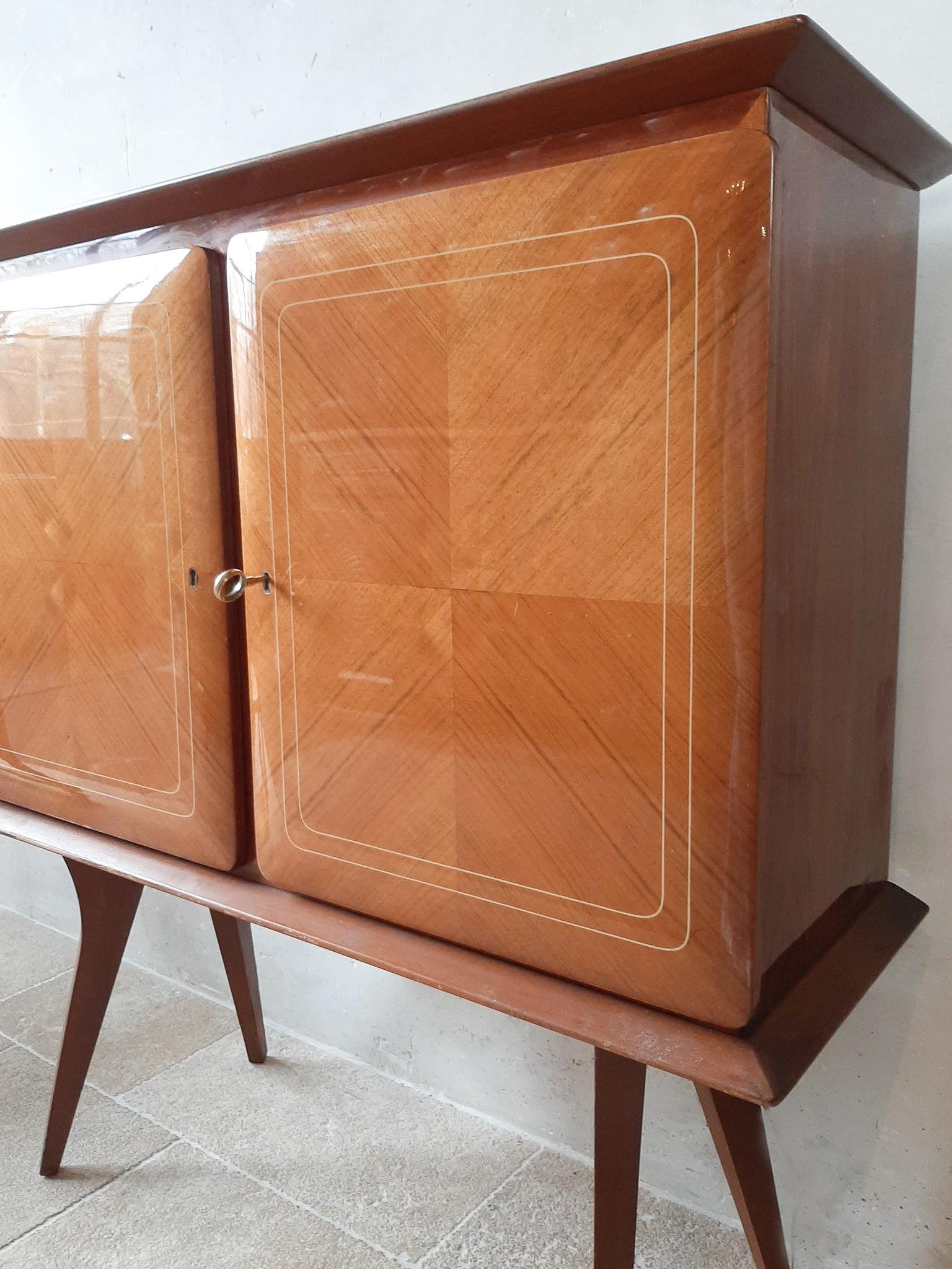 Italian vintage Paolo Buffa liquor cabinet from the 1950s. A mid-century bahut or bar cabinet in massive walnut and applied walnut veneer. The two doors have an open leaf pattern and resin inlay; they open with the key. The left side houses four