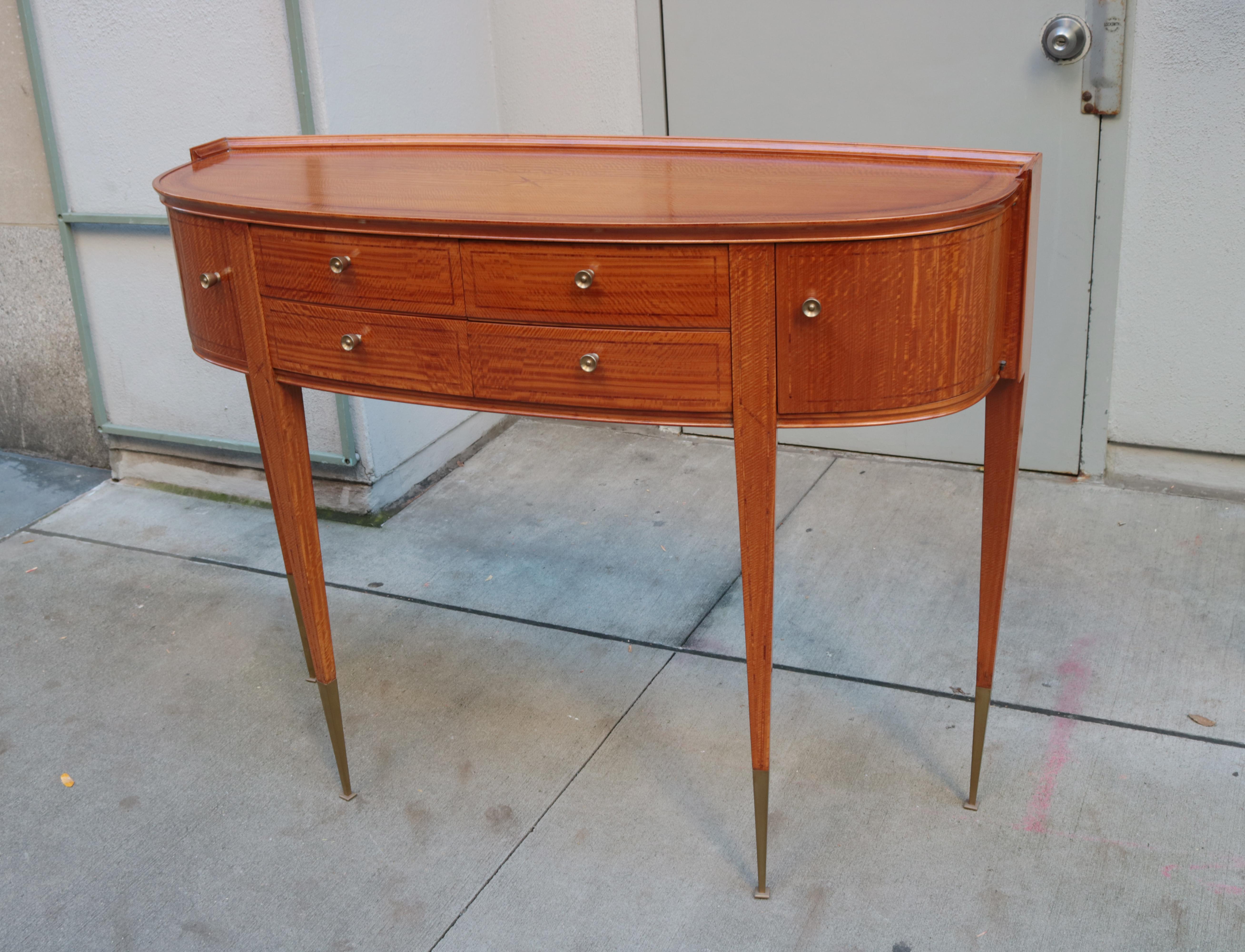 An Italian midcentury wall console.
Four central drawers flanked by curved doors.
Tiger maple with fruitwood inlay details, patinated brass pulls and sabots.